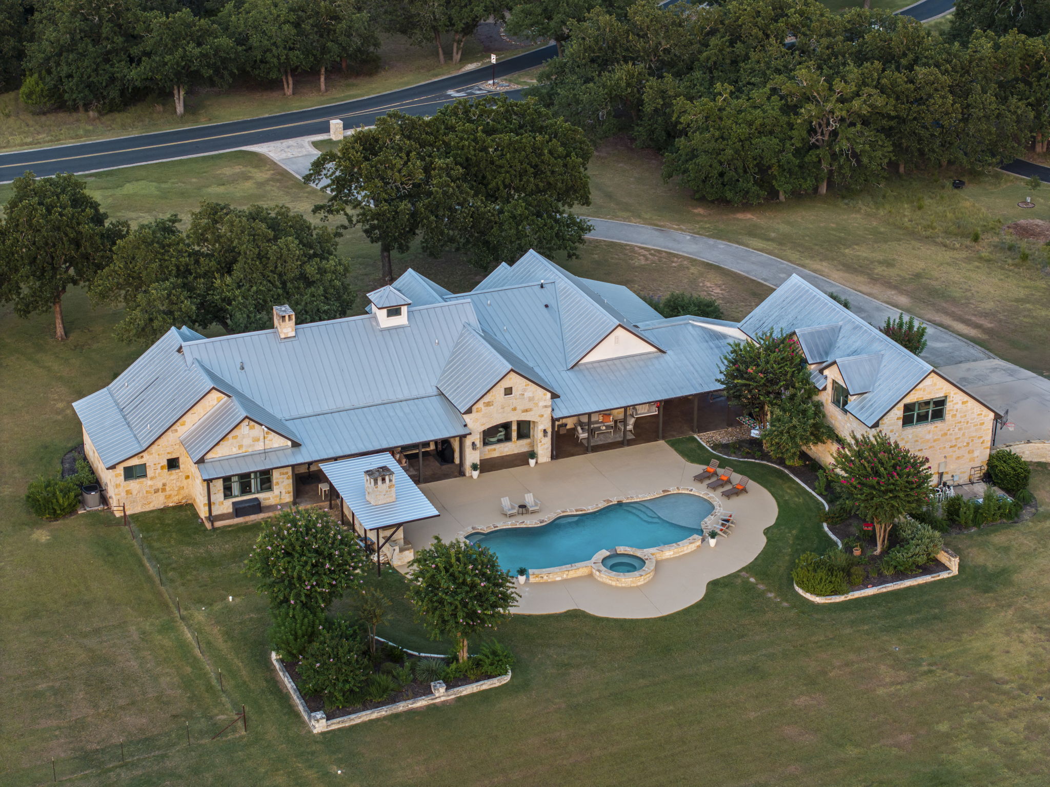 Bird's-eye perspective of a beautiful home and its expansive grounds, featuring a sparkling swimming pool and hot tub.