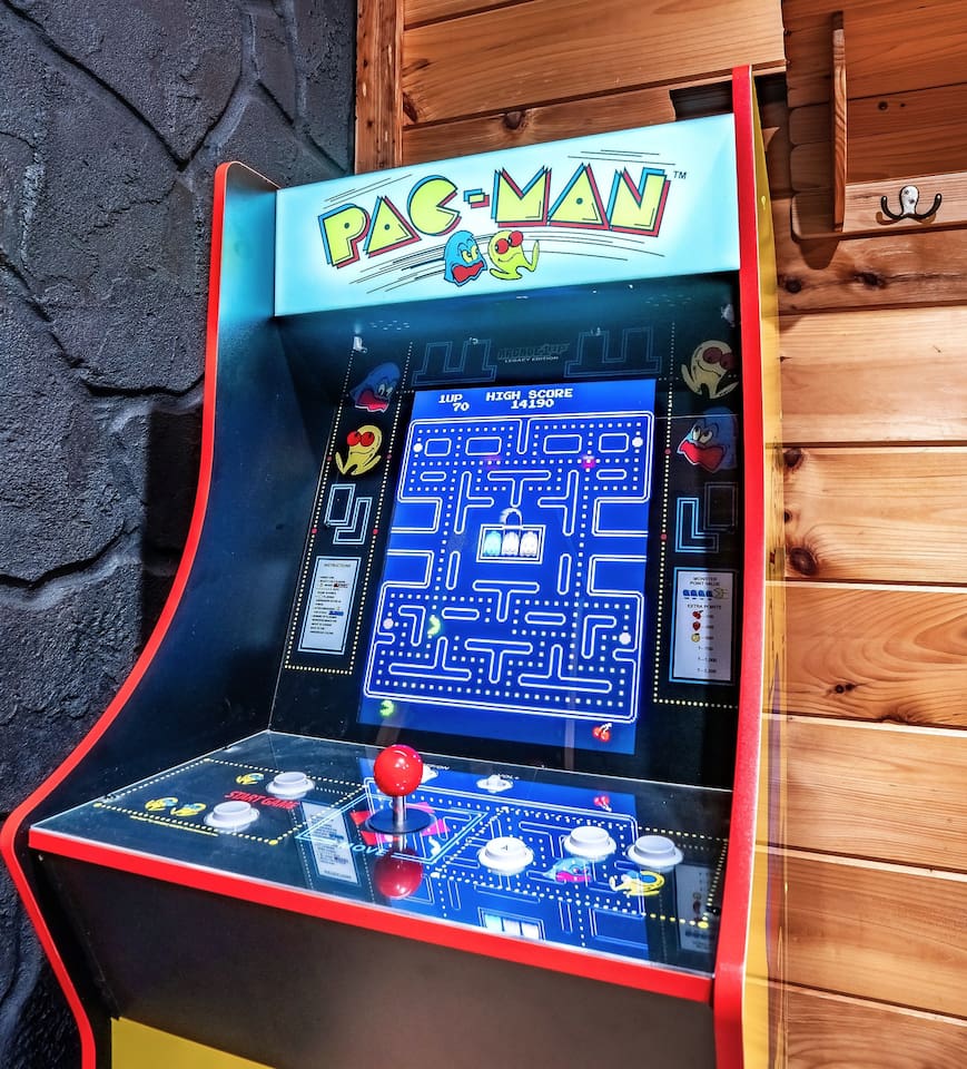 Charming mountain cabin with an arcade machine in the game room, offering playful entertainment for guests of all ages in a mountain scenic retreat.