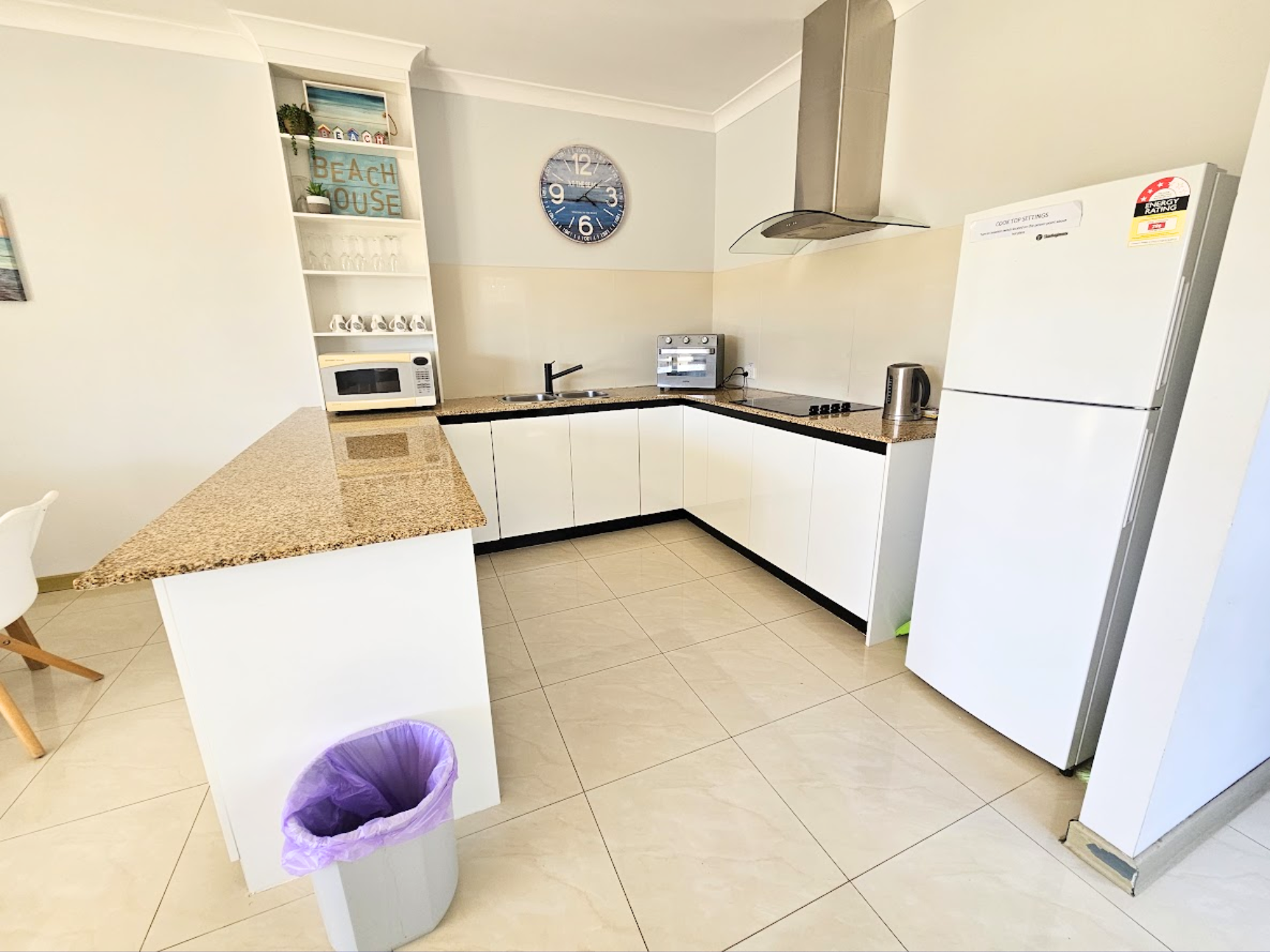 Large kitchen with electric stove top, full size fridge and coffee machine