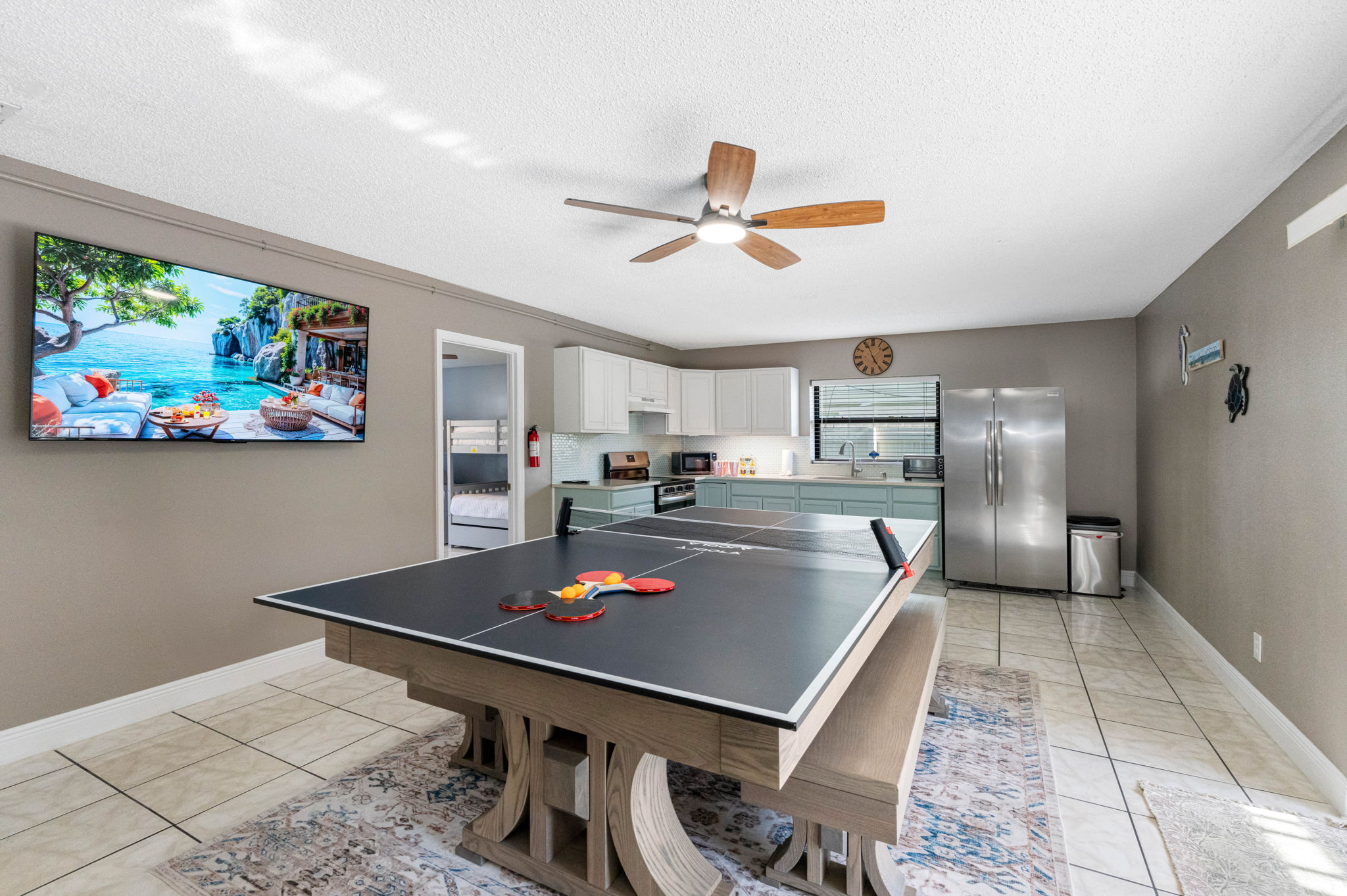 At the center of the room is a modern farmhouse-style table that transforms effortlessly from a dining space to a full-size ping pong table.