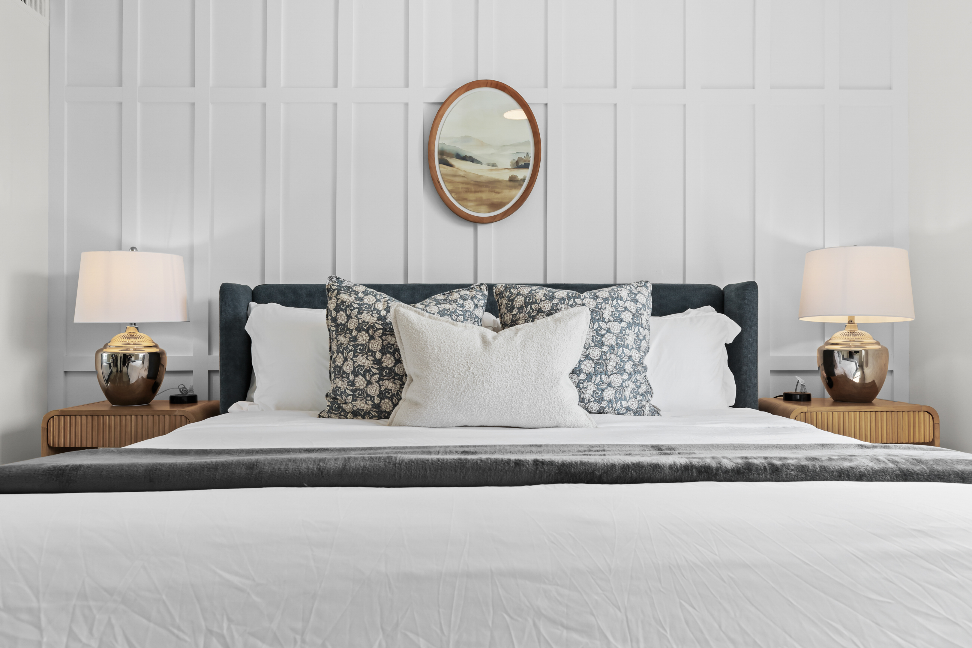 Luxurious king bed with soft linens and modern panel wall backdrop.