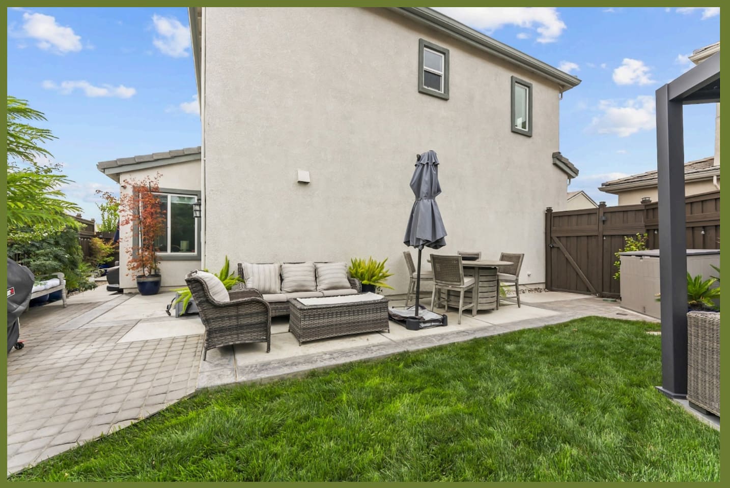 Backyard patio with lounge seating, umbrella shade, and open lawn space for relaxing outside.