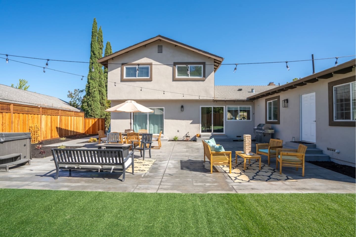 Backyard with hot tub, outdoor dining and seating with fire pit.
