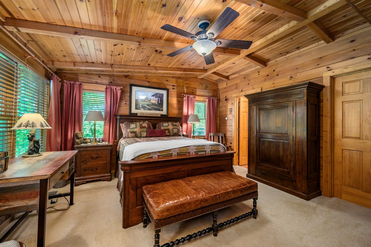 Master bedroom featuring a spacious king bed, rich wood interiors, and cozy rustic furnishings.