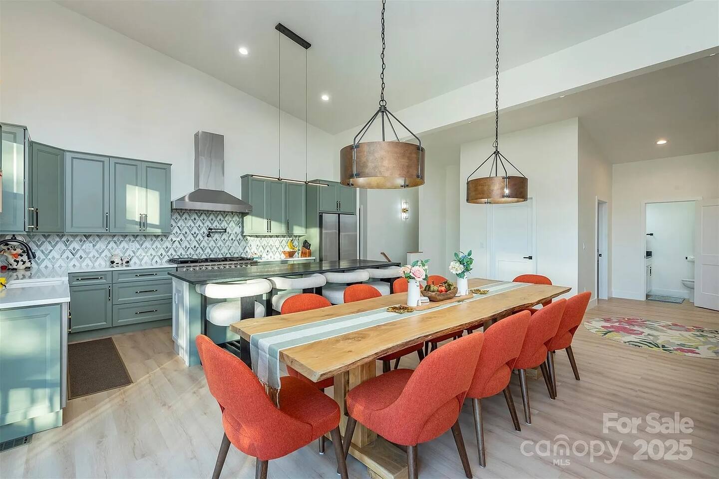 Spacious open-plan layout featuring a large dining table, stylish upholstered seating, a gourmet kitchen with oversized island, and modern lighting, perfect for family meals and group getaways