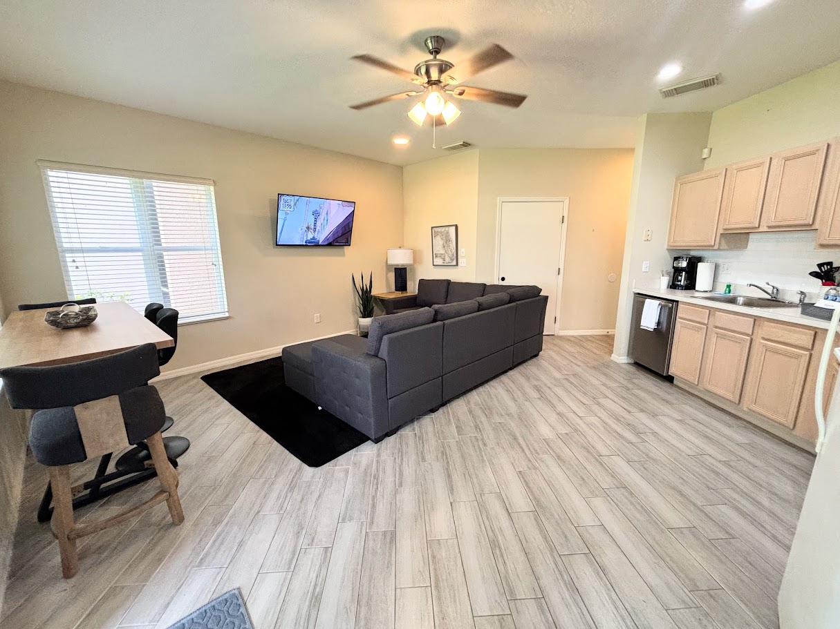 Open living and dining space with updated flooring, cozy seating, and a bright kitchen layout.