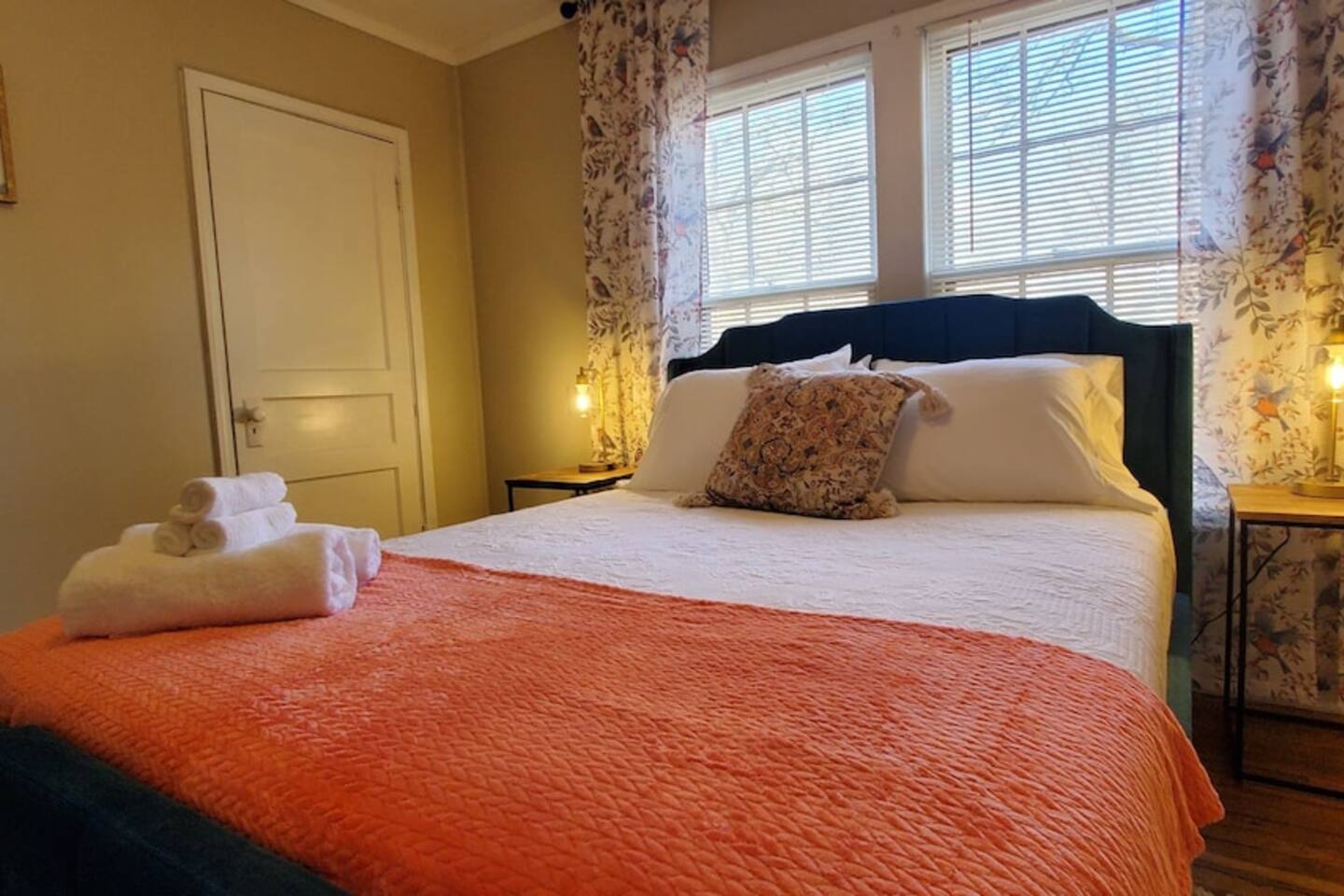 Inviting bedroom with a plush velvet bed, soft linens, bedside lighting, and a welcome basket of towels—perfect for a restful stay.