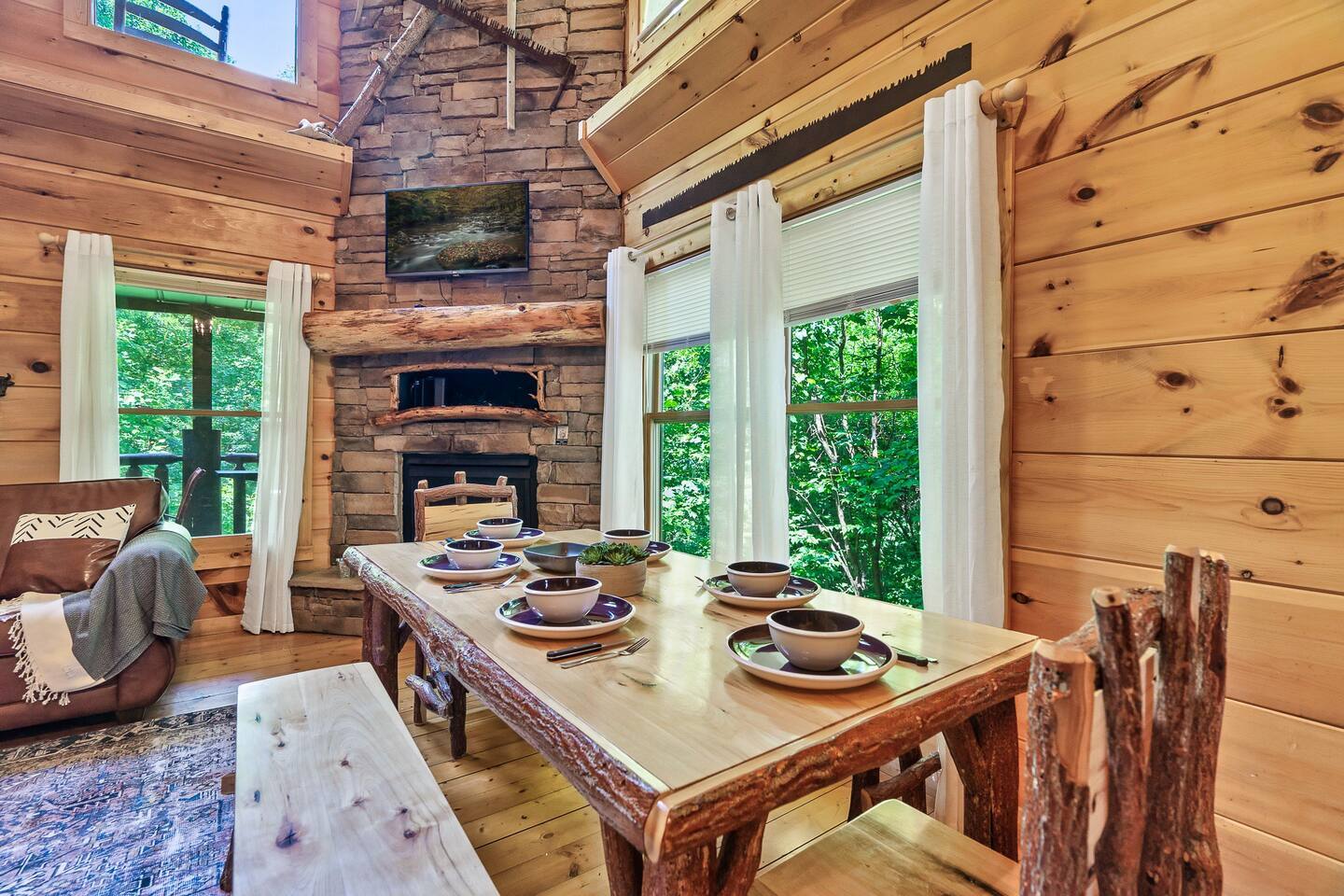 This rustic 6-seater dining area, complete with a wooden table and benches, seamlessly complements the warm tones and holiday decor of the surrounding cabin interior.