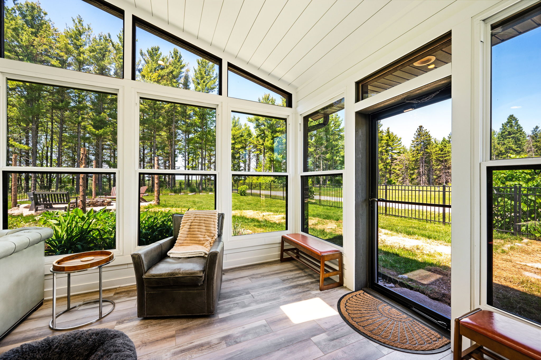 Relax in the light-drenched sunroom, where a plush leather chair and wall of windows invite you to unwind with a book and a view.