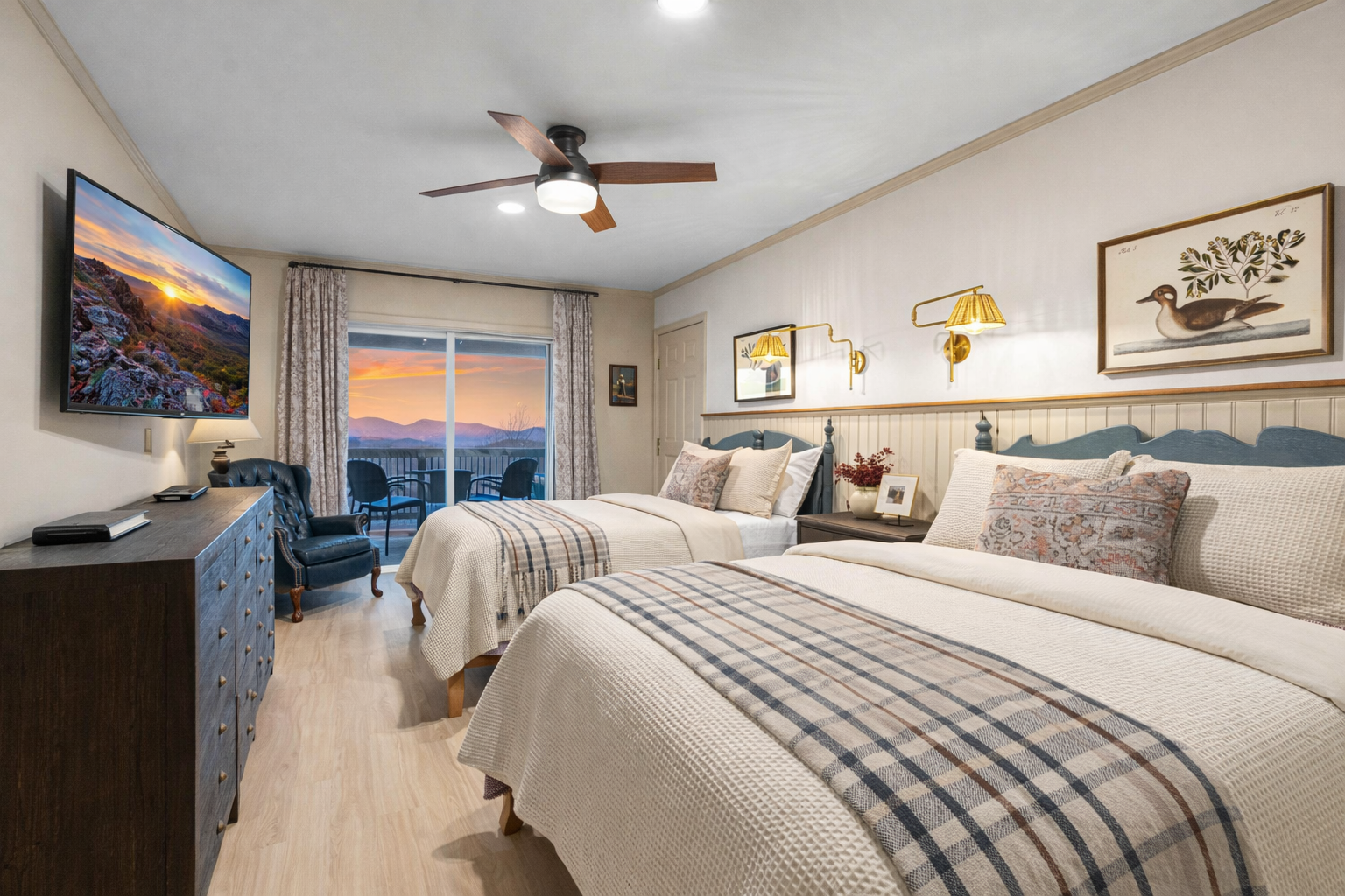 Fisherman’s Room with three queen beds, wall-mounted TV, and sliding doors to the covered porch—comfortable, spacious, and ideal for group stays.
