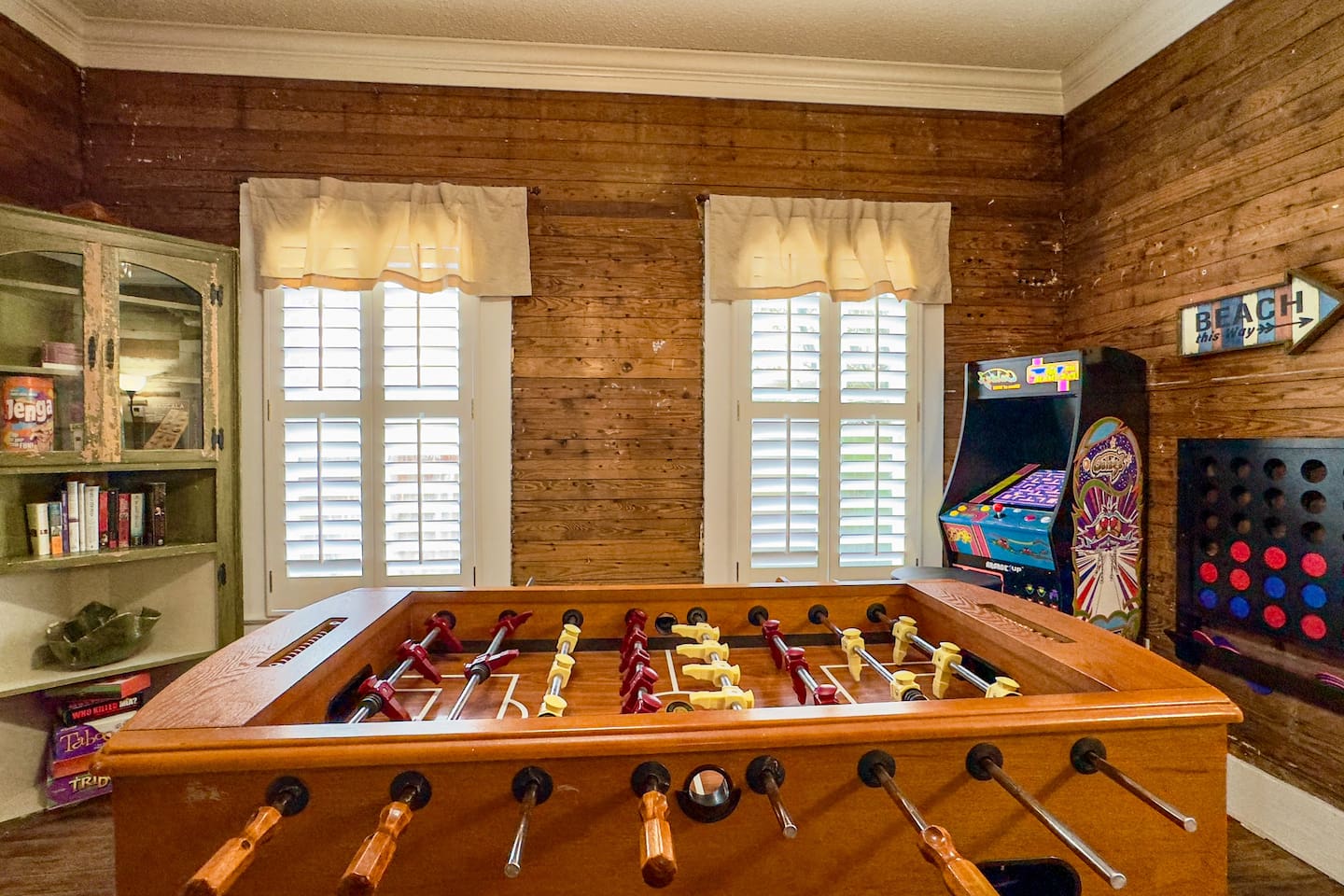 Entertaining game room with a foosball table, arcade games, and rustic wood accents—perfect for friendly competition.