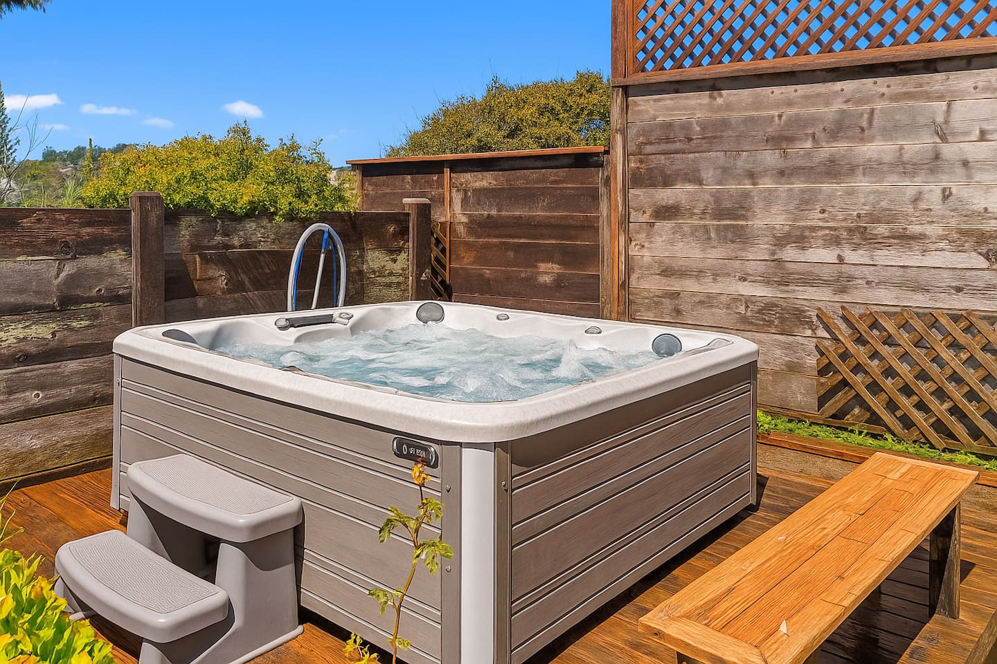 - Private hot tub area with wooden deck and seating for relaxation  
- Surrounded by fencing and greenery for added privacy and comfort  
- Perfect spot to unwind after a day of beach walks or local adventures