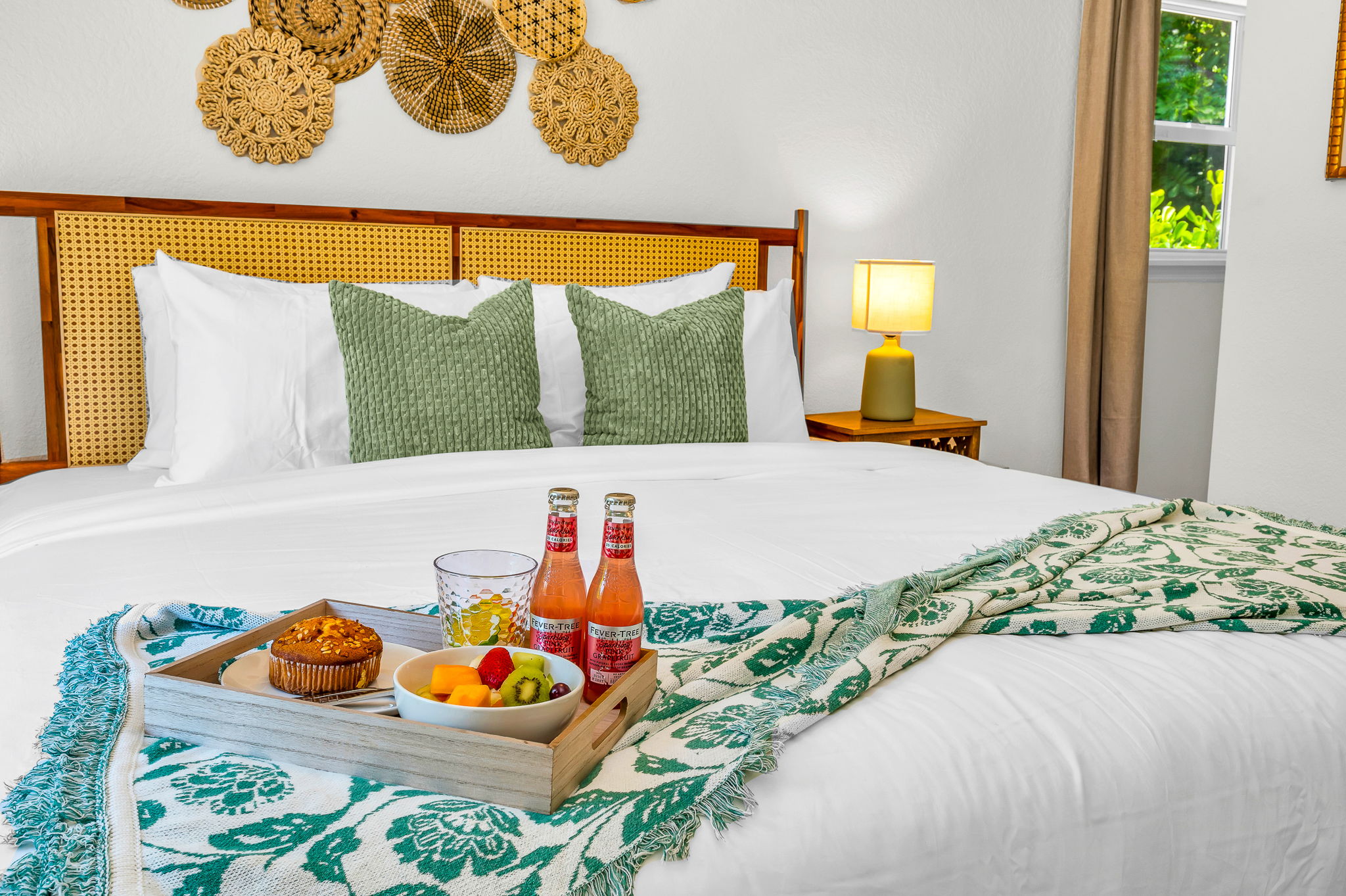 Serene ensuite primary king suite featuring a plush bed with luxury linens, vaulted ceilings with exposed beams, and elegant coastal décor. Includes a spacious walk-in closet with washer and dryer for added convenience and comfort.