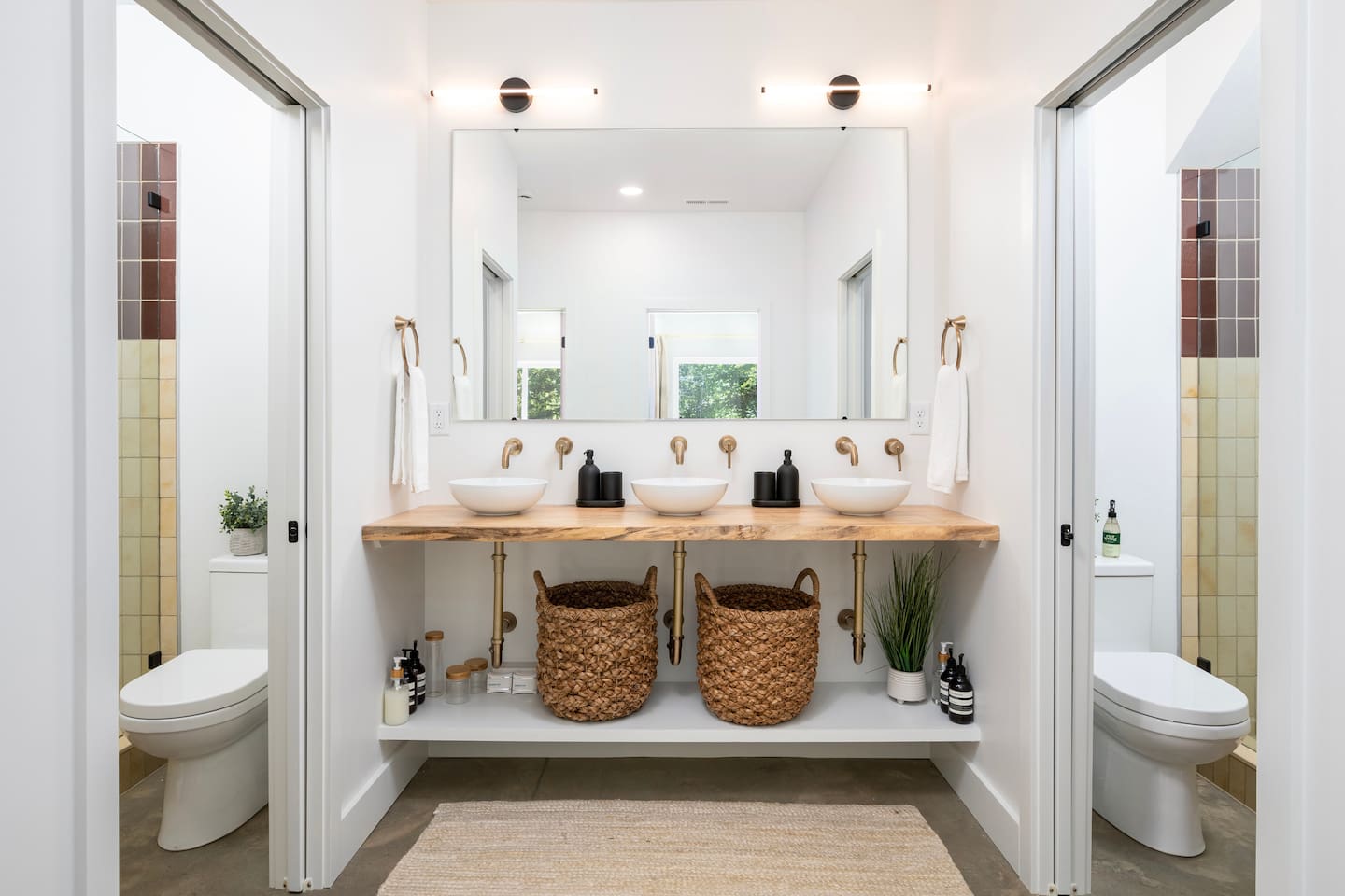 Downstairs bathrooms with 2 private shower/toilet combos on either side and 3 open sinks for multiple guests. 