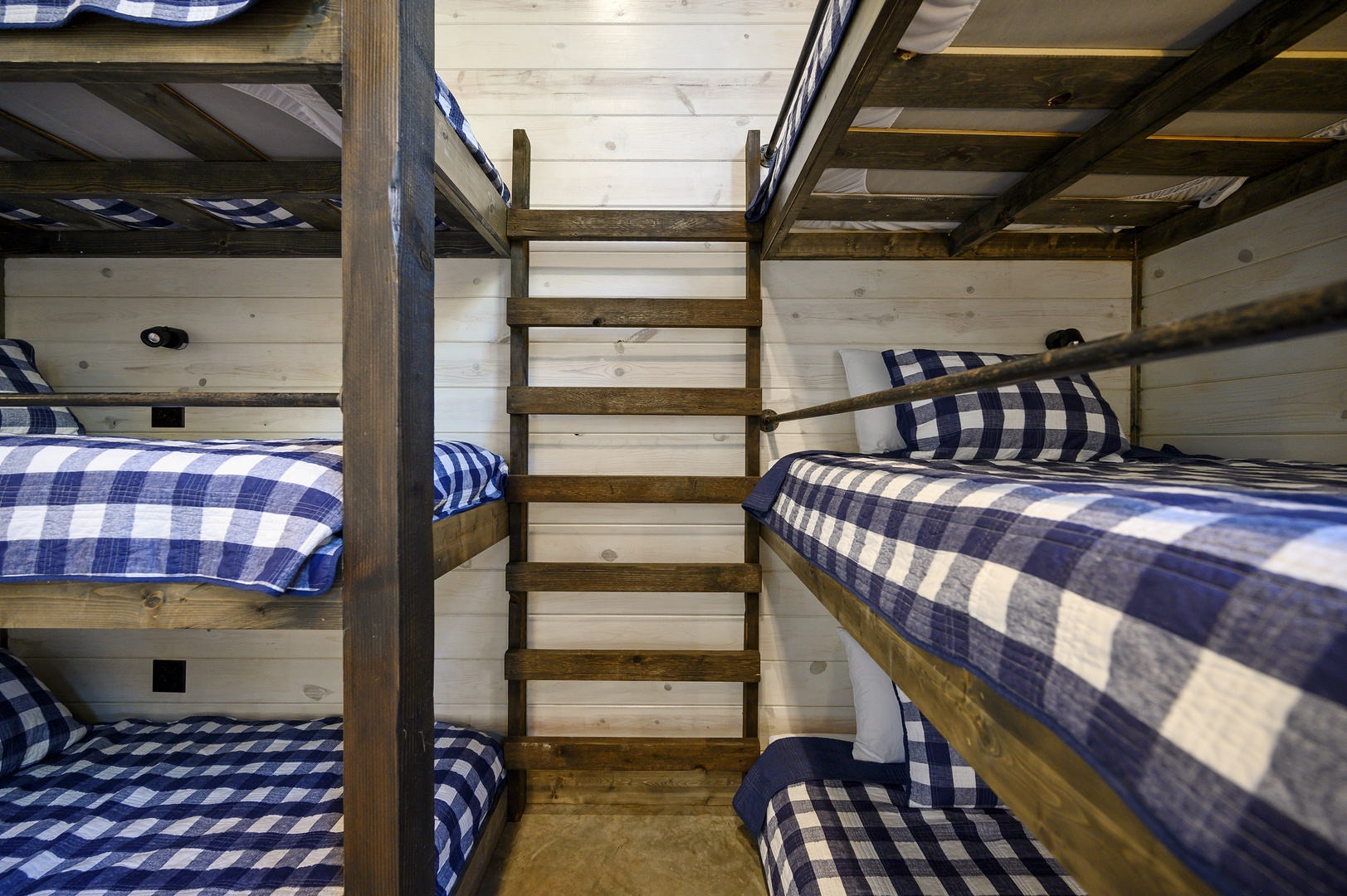 Crisp plaid bedding and custom-built bunks bring charm and comfort to this inviting shared space.