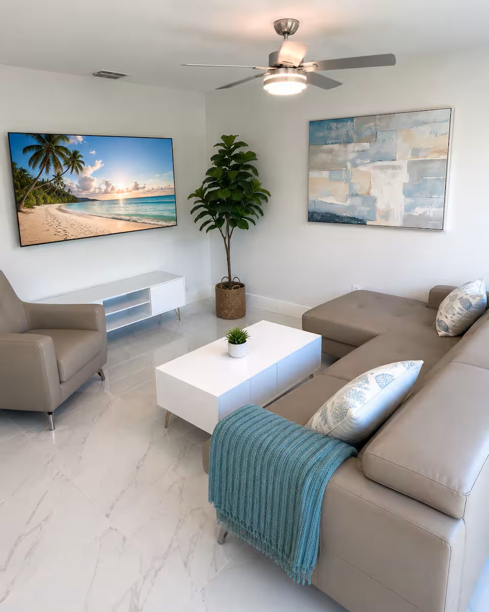 Bright, modern living room with comfortable seating, a large smart TV, and a relaxing coastal feel.