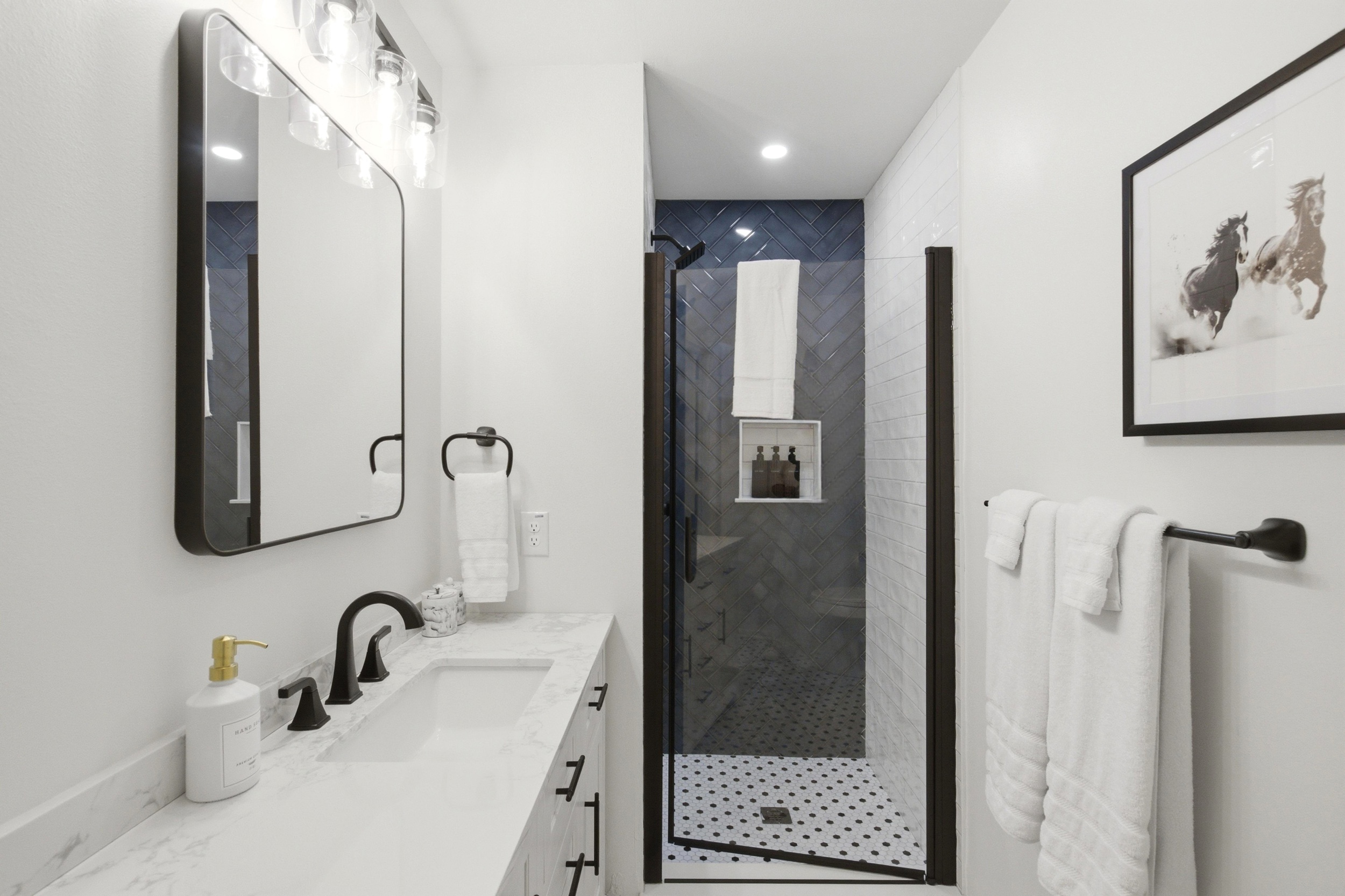 Spacious Bathroom 2 with bright Single Vanity, large mirror, and Standing Shower. Stocked with essentials by Ginger Lily Farms, fresh towels, and Hairdryer.

