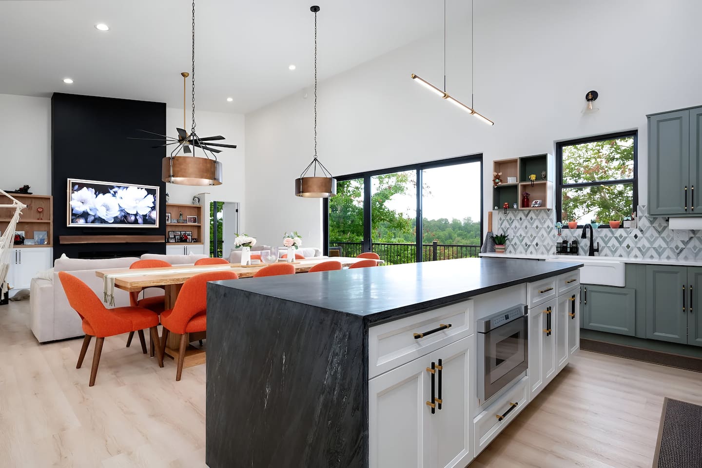 A bright, open-concept living space with a large kitchen island, modern pendant lighting, and seamless flow into the dining and living areas, ideal for family gatherings, group stays, and entertaining in style.