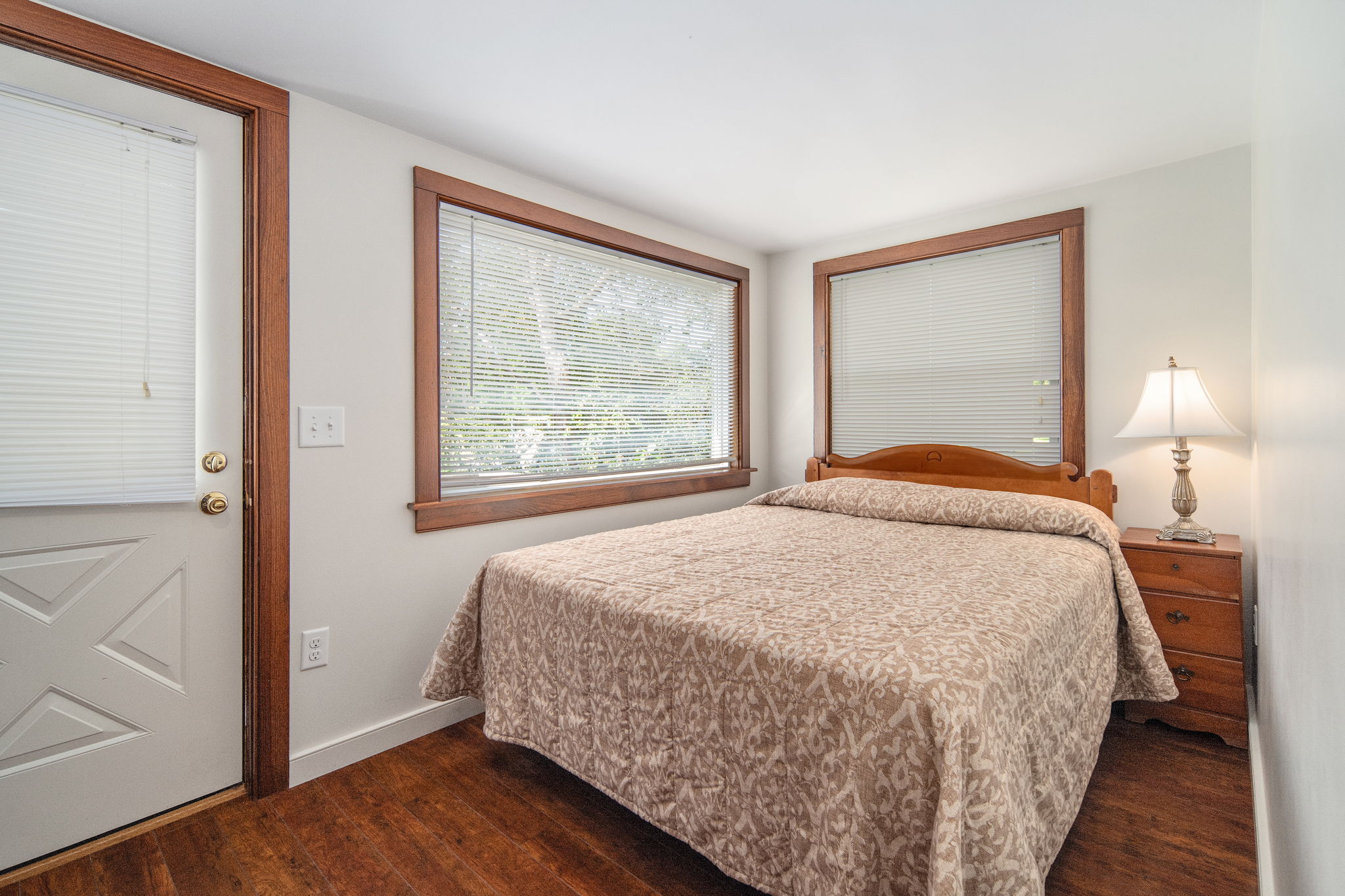 A cozy queen bedroom with natural light and warm wood accents.