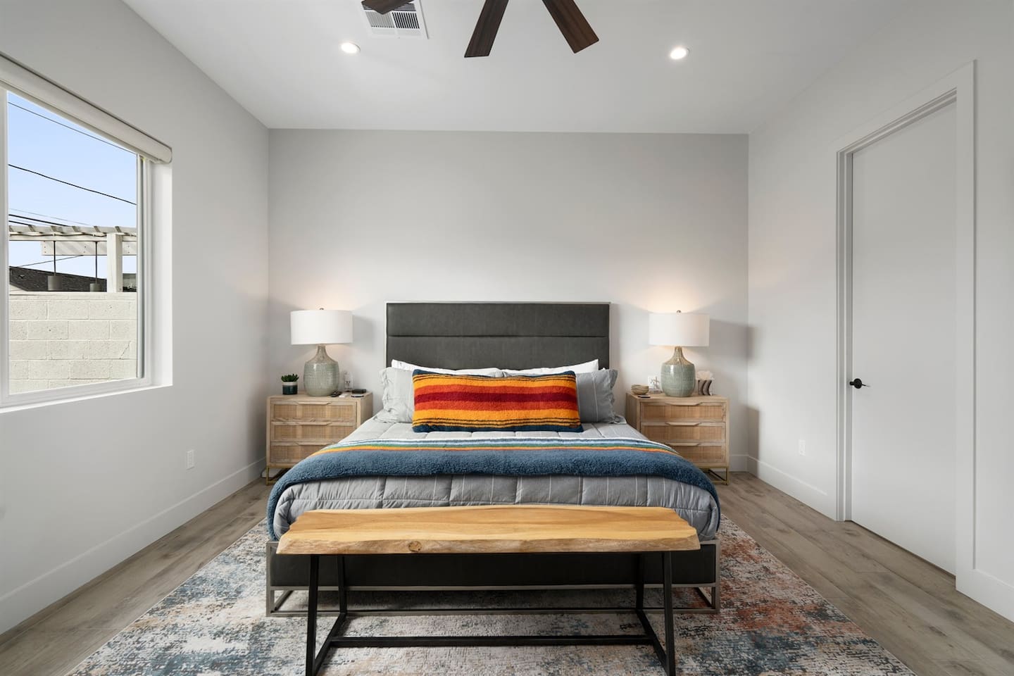 Relax in the cozy bedroom, featuring a comfortable bed flanked by two side tables, a ceiling fan for added comfort, and a TV for your entertainment needs.