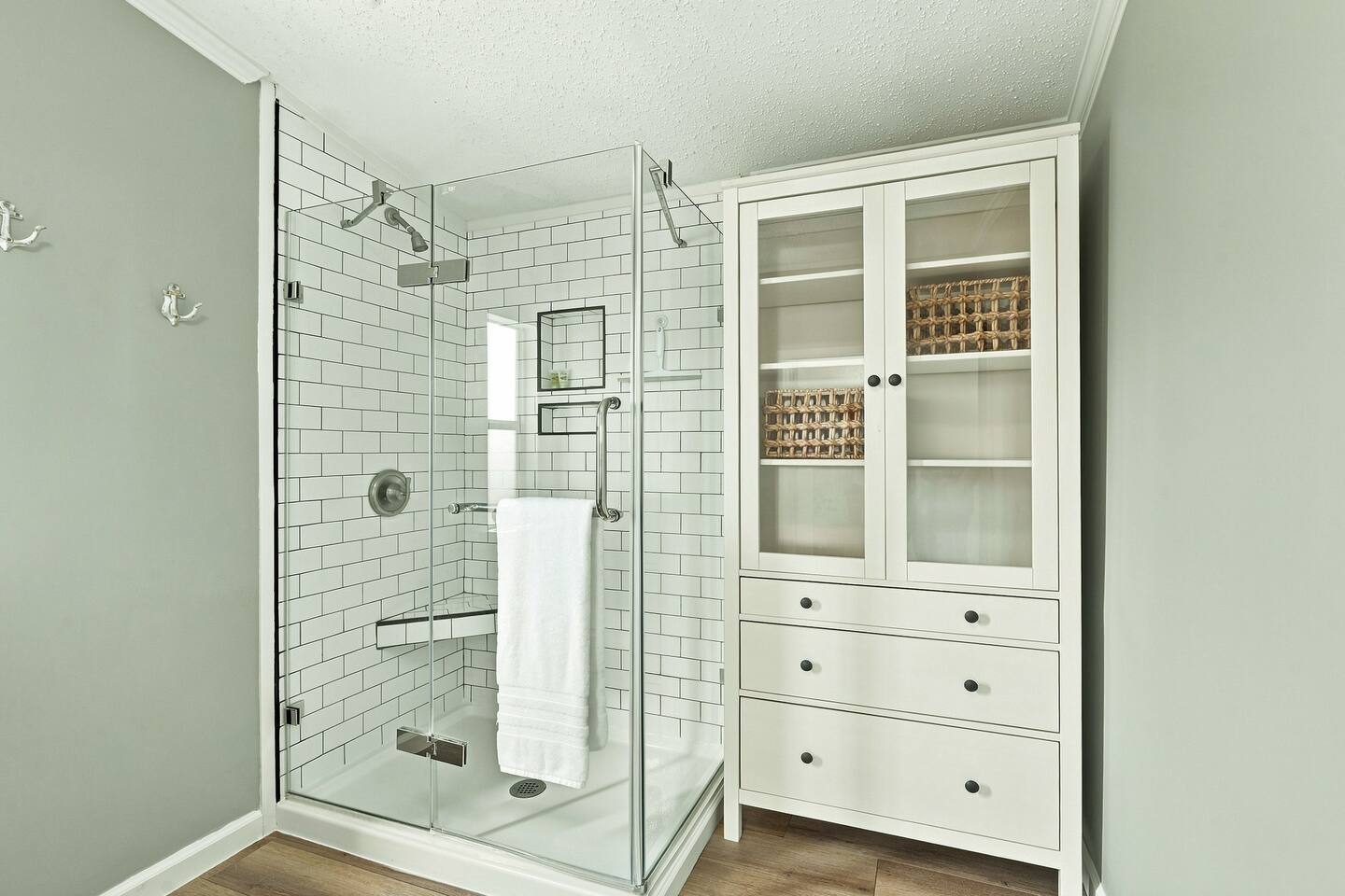 Step into the glass-enclosed walk-in shower, with built-in shelving nearby for convenient bathroom storage during your stay.
