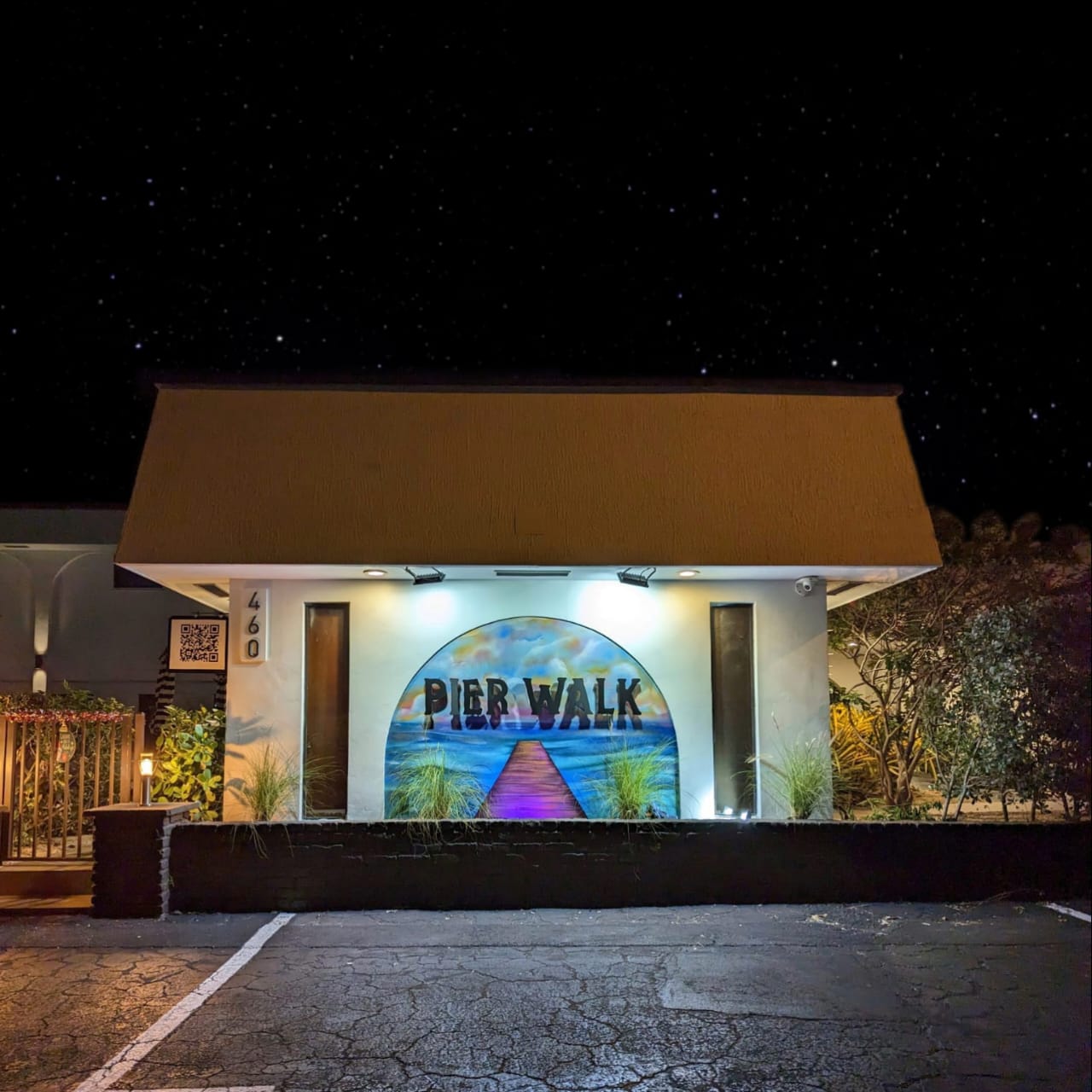 Evening photo of our Pier Walk sign and custom mural lit up with LED lights. QR sign hangs on the left.
