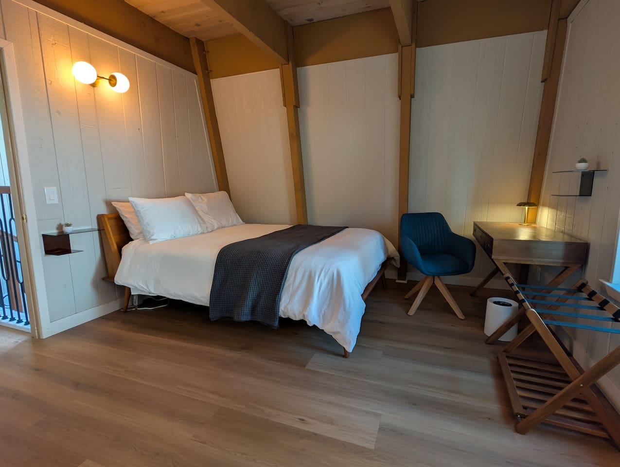 This modern A-frame room pairs a plush bed with a remote-ready desk setup and a convenient luggage rack.