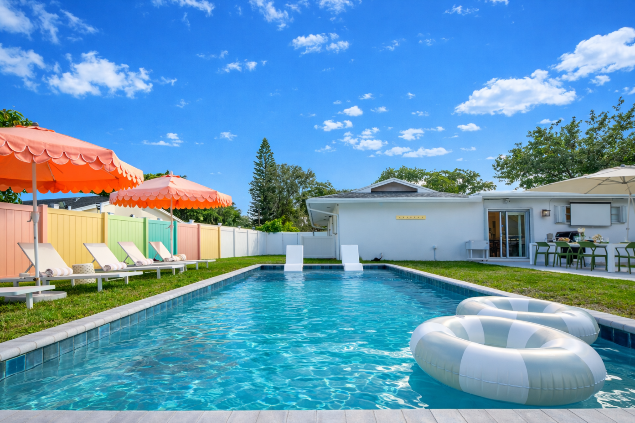 A sun-drenched Palm Beach oasis—brand-new heated saltwater pool with chic in-pool loungers, plush sunbeds, and iconic peach umbrellas, all set within a private, resort-style backyard made for long, lazy afternoons.