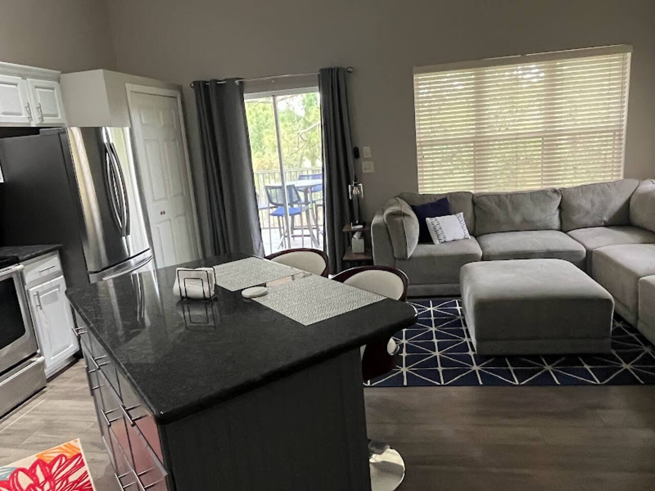 Open kitchen and living space with updated finishes, breakfast bar seating, and natural light from the balcony doors.