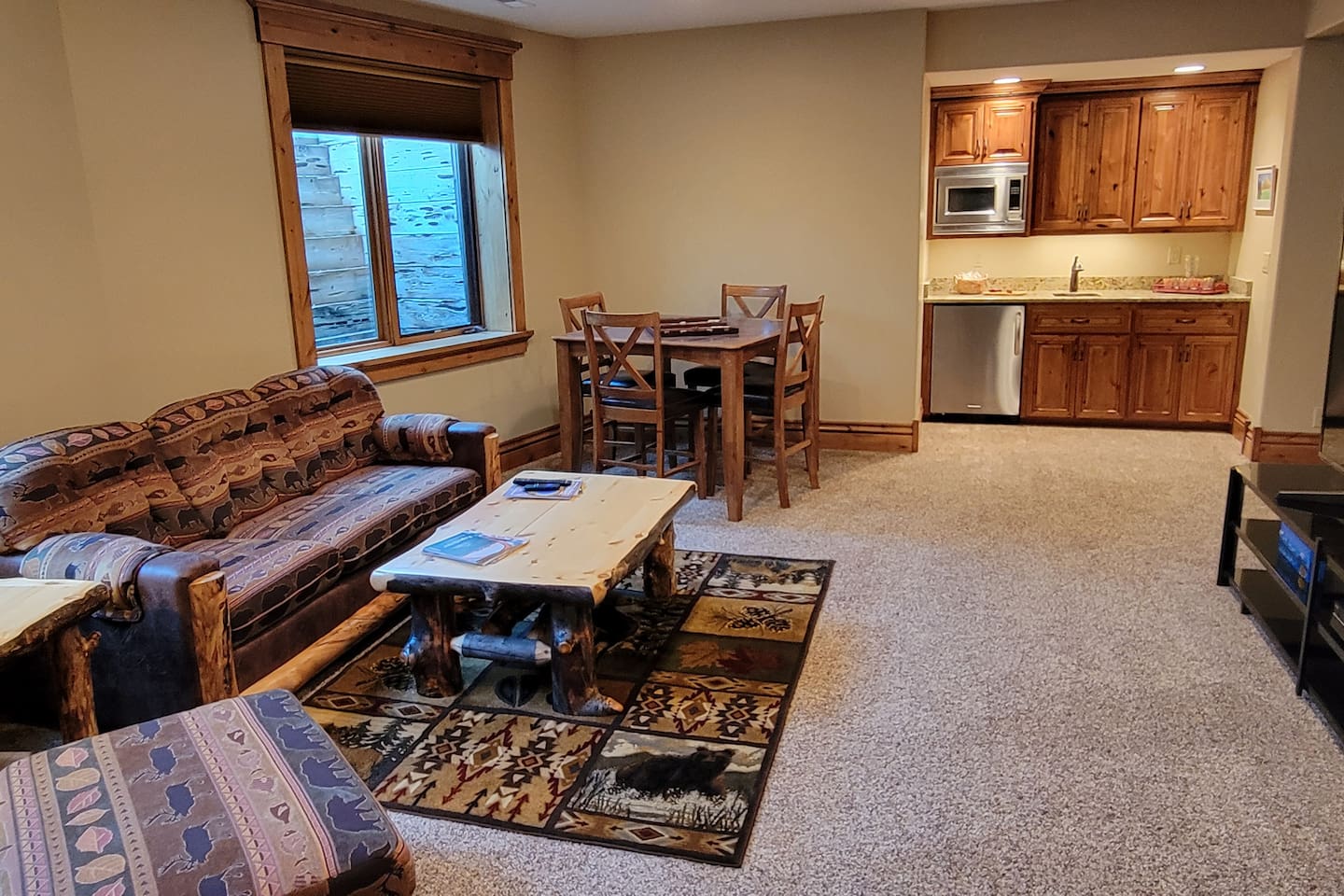 This inviting lower-level space serves as a perfect second living area, offering comfortable seating, a dining table, and a convenient kitchenette. Ideal for relaxing, movie nights, games, or creating additional gathering space! 