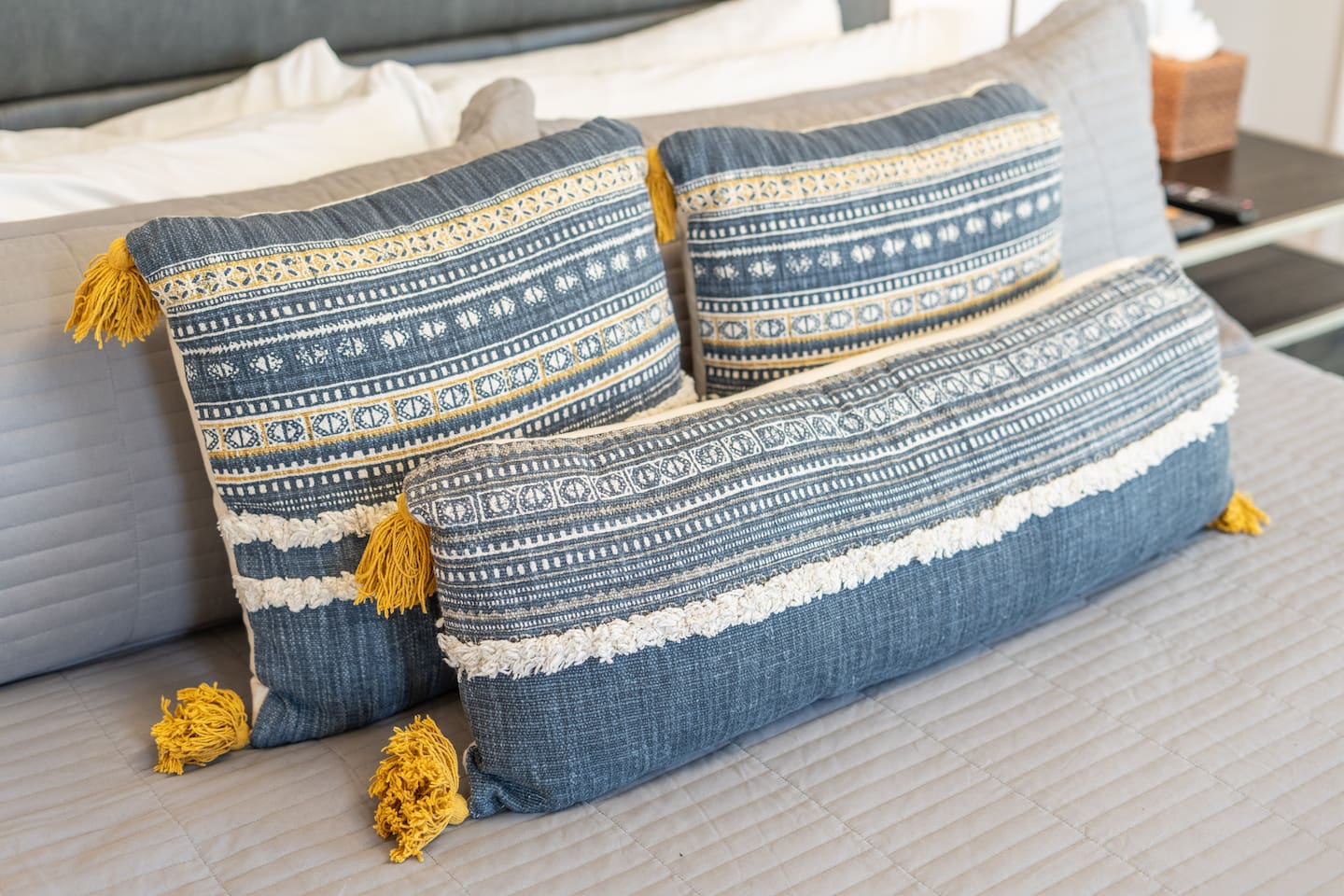 A close-up of the bed's plush decorative pillows featuring intricate patterns and mustard-yellow tassels for a playful yet polished finish.