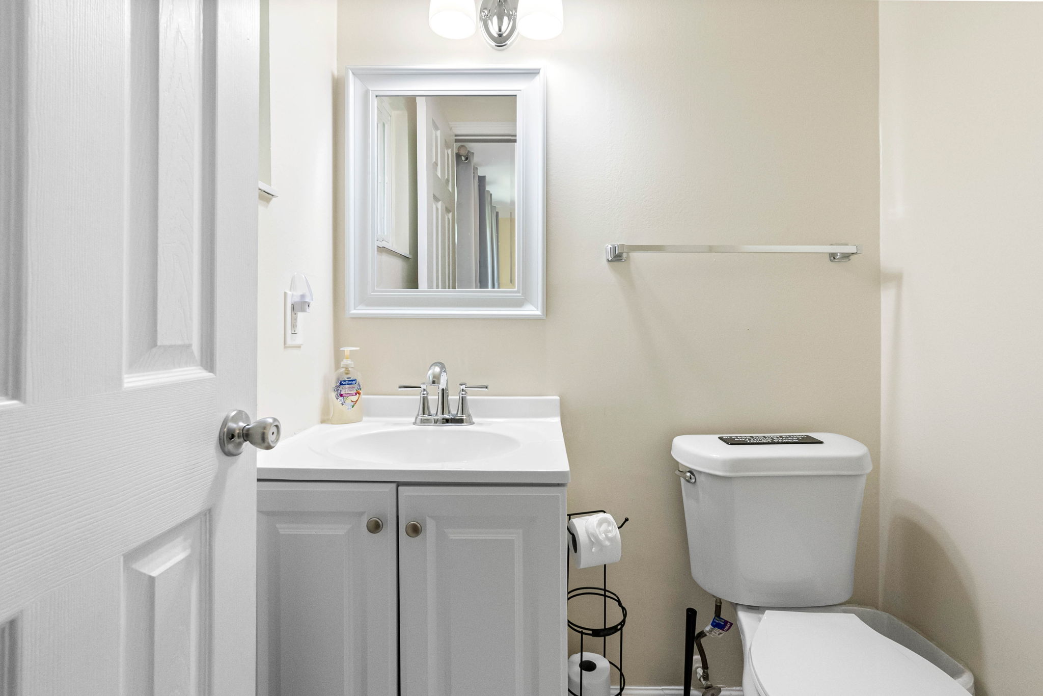 The white vanity features classic paneled cabinet doors and a smooth, solid-surface countertop with an integrated sink.
