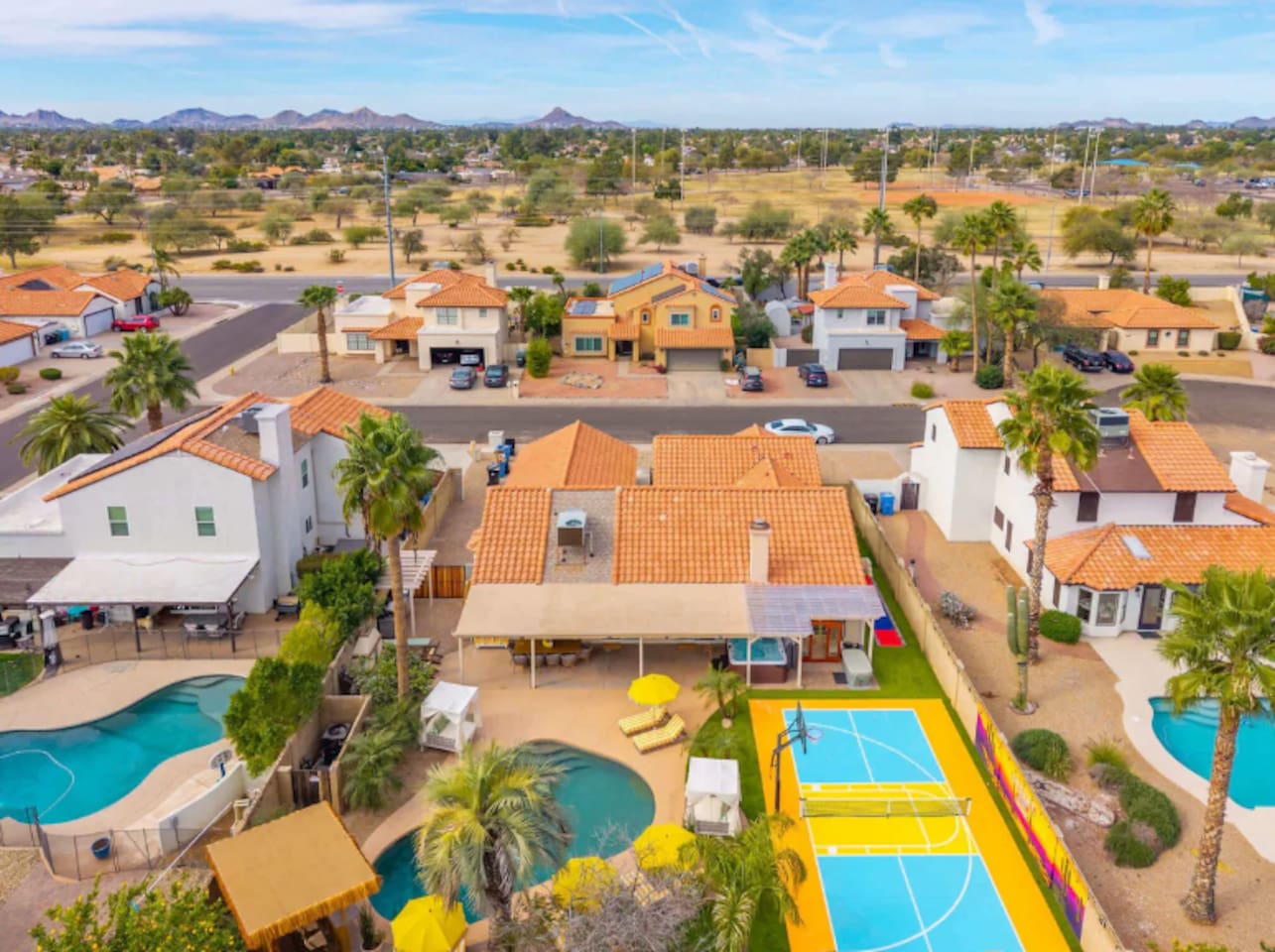 An aerial view says it all — pool, putting green, lounge seating, and desert views across this resort-style backyard.
