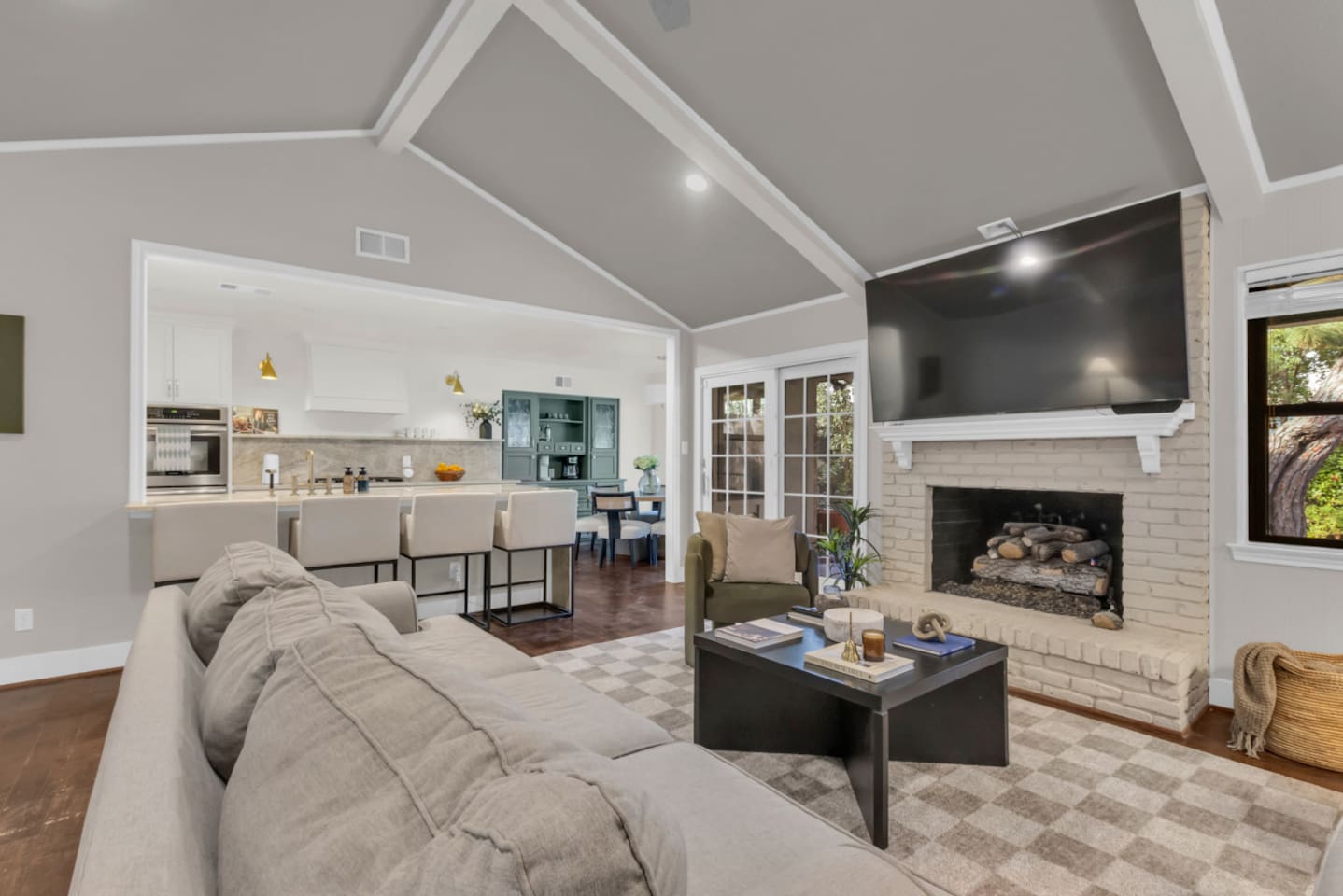 Open-concept living room designed for comfort and connection, featuring spacious seating, a cozy gas fireplace, and a 70” Smart TV. The layout flows seamlessly into the kitchen and dining areas, creating an inviting space for relaxing, entertaining, 