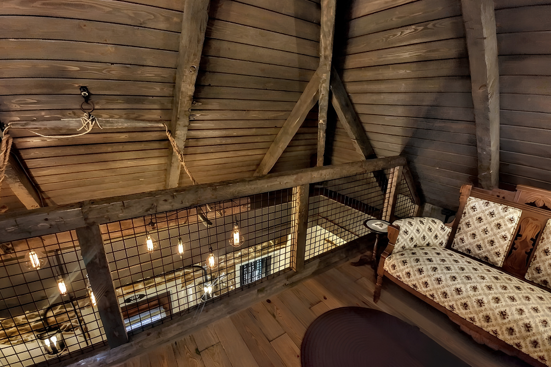 Upper Level Bedroom seating area opens to the living area on the historic house main level just past railing