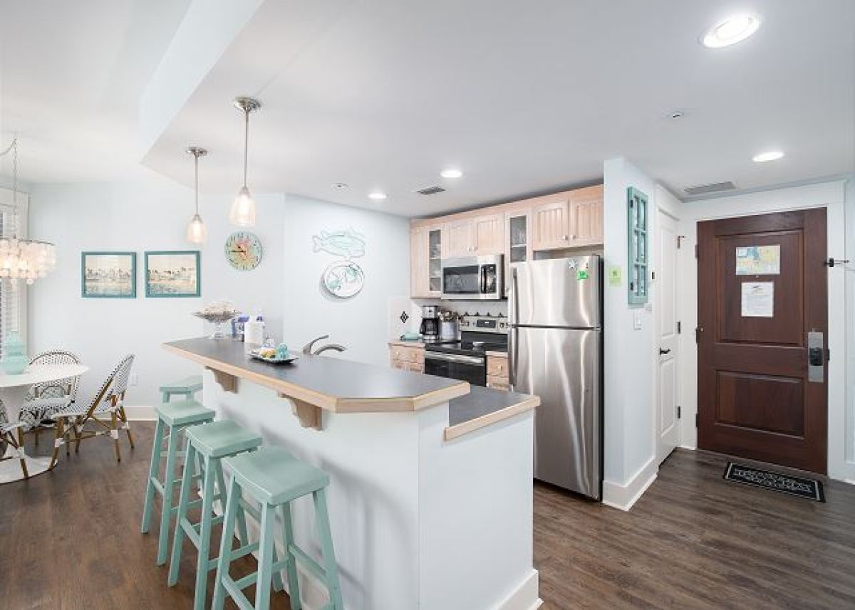 Full kitchen with breakfast bar seating for three, stainless appliances and the entry door