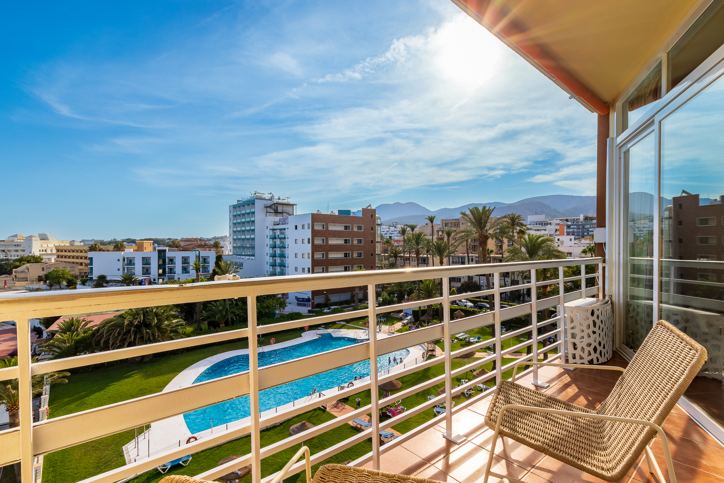 Balcony view over the shared pool, palms, city and mountains.