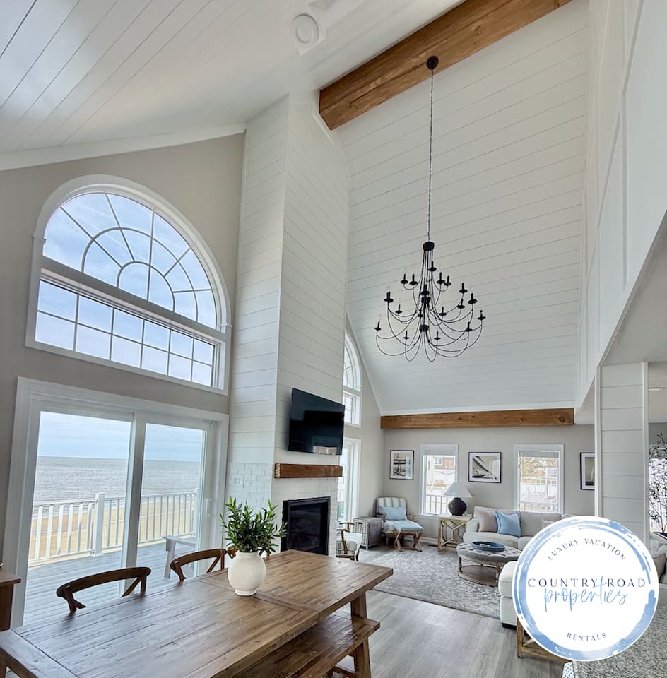 Experience luxury in this open-concept living space. With soaring ceilings, a statement chandelier, and stunning ocean views through floor-to-ceiling windows, it’s the perfect coastal retreat for elegant relaxation.