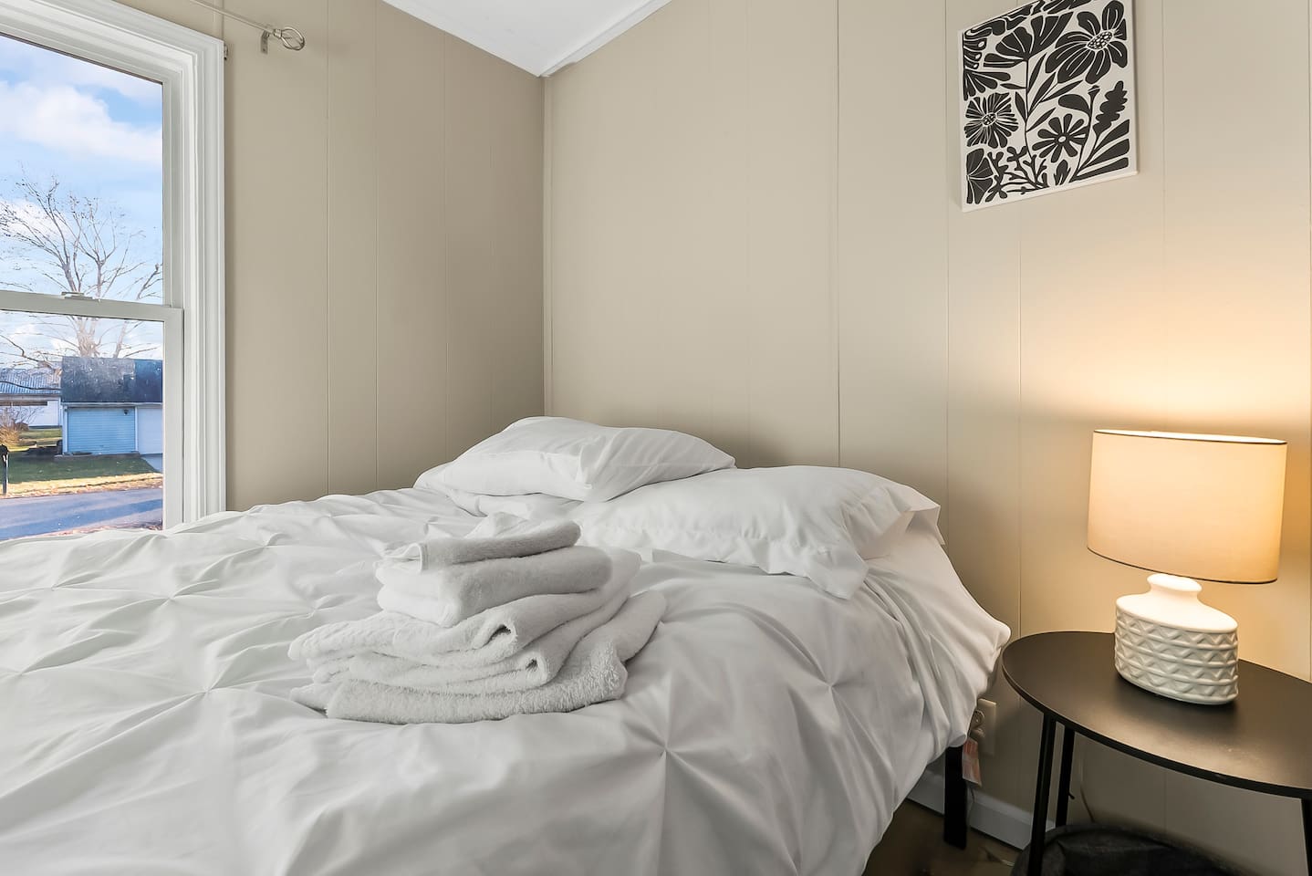 Thoughtfully prepared guest bed with bedside lamp and window views.