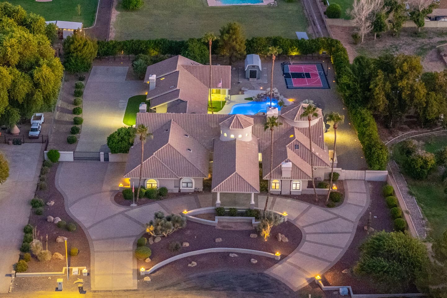 Capture the beauty of this expansive retreat featuring a glowing pool, full-size sports court, and lush landscaping.