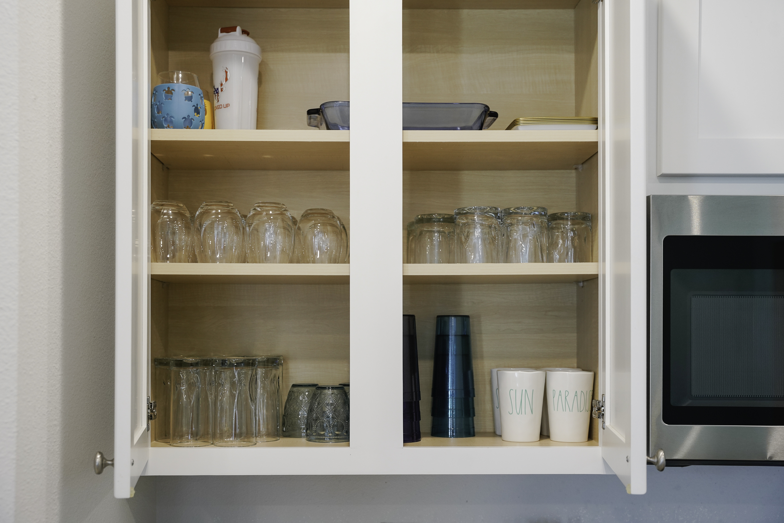 Fully stocked kitchen with utensils, plates, cups, and glasses