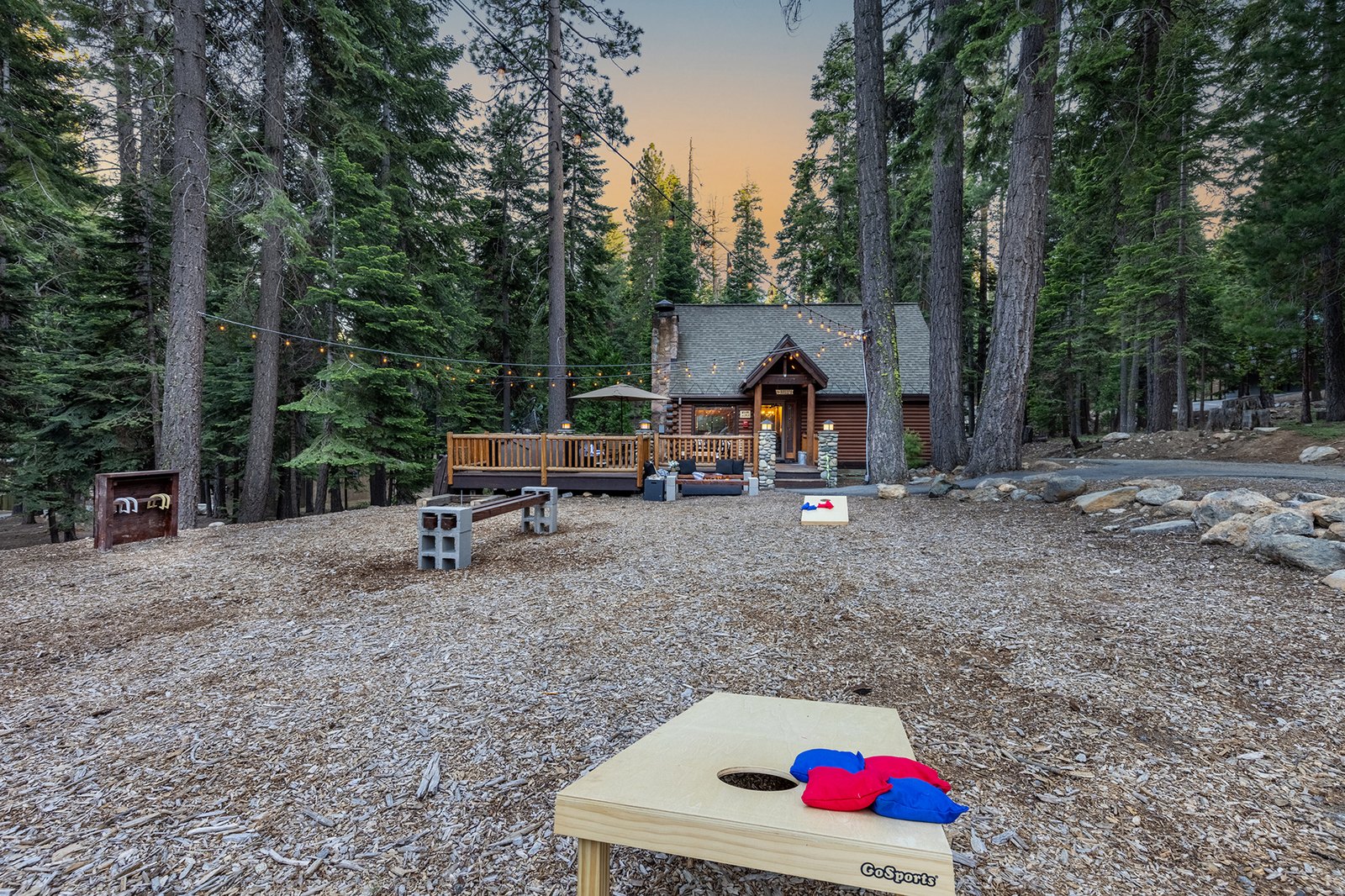 Toss the last round of cornhole as the lights come on and the cabin glows gold through the pines — this is the evening you booked it for.