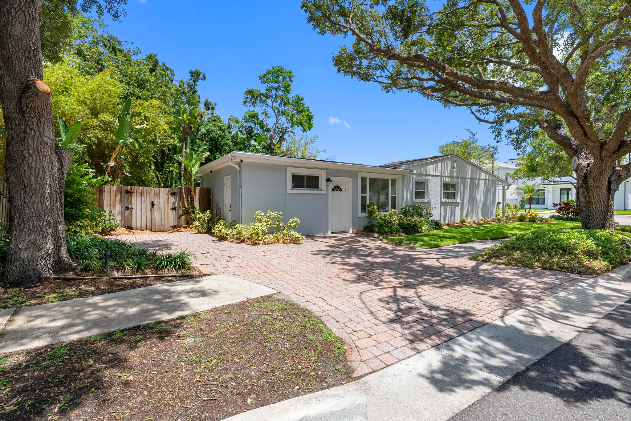 A brick-paved walkway curves gently through a manicured front lawn, leading you to the cheerful blue front door—a bold pop of color that welcomes guests with warmth and character.