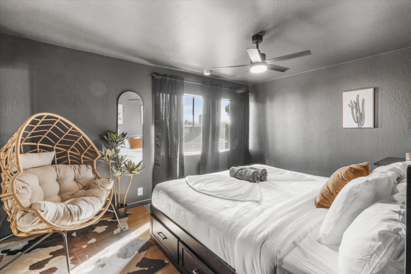 King bedroom with soft linens, ceiling fan, accent chair, and window light for a relaxed stay.
