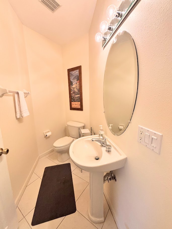Convenient half bathroom with pedestal sink, tile flooring, and clean neutral finishes.