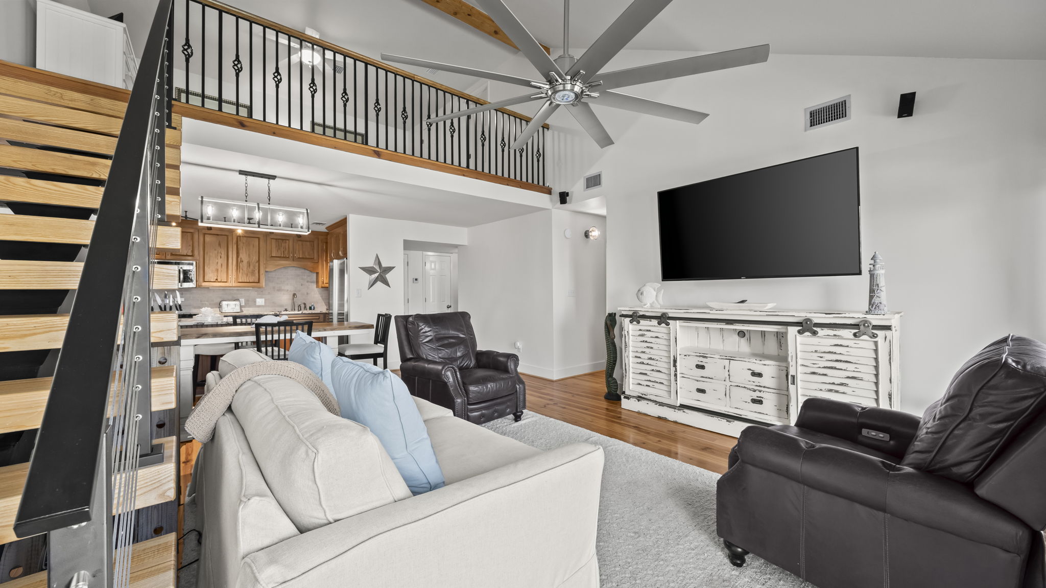 Unwind in the living room of our Cotton Bayou condo, featuring a comfortable couch and cozy recliners, perfect for relaxing after a day of coastal adventures. Enjoy modern decor, a smart TV, and a welcoming atmosphere.