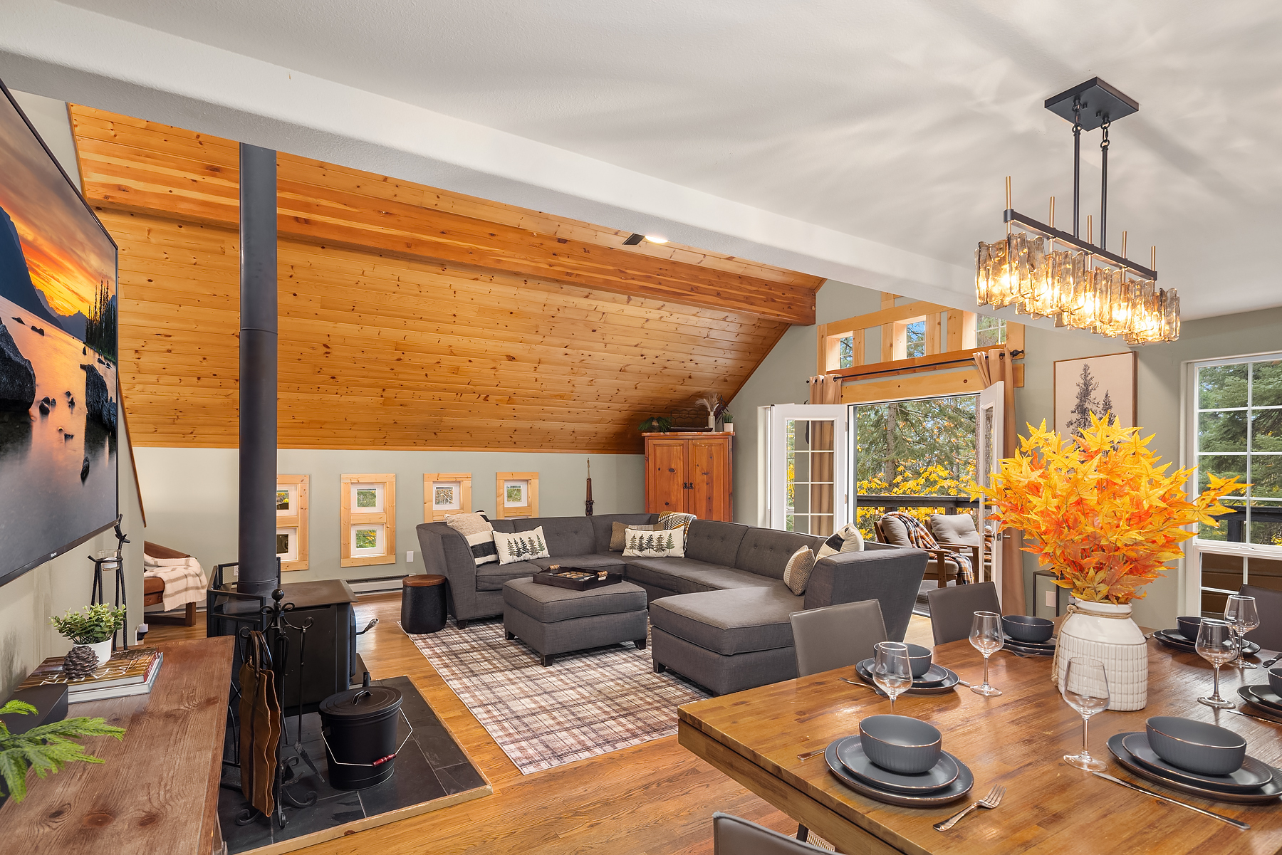 Open living room and dining room with wood burning stove and French doors to the upper deck
