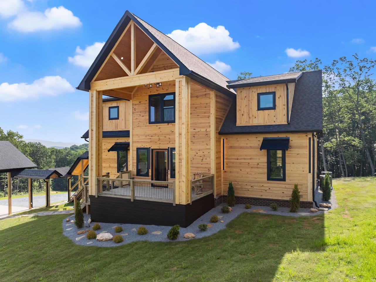 A closer look at the stunning exterior showcases natural wood finishes, black trim, and manicured stone accents.