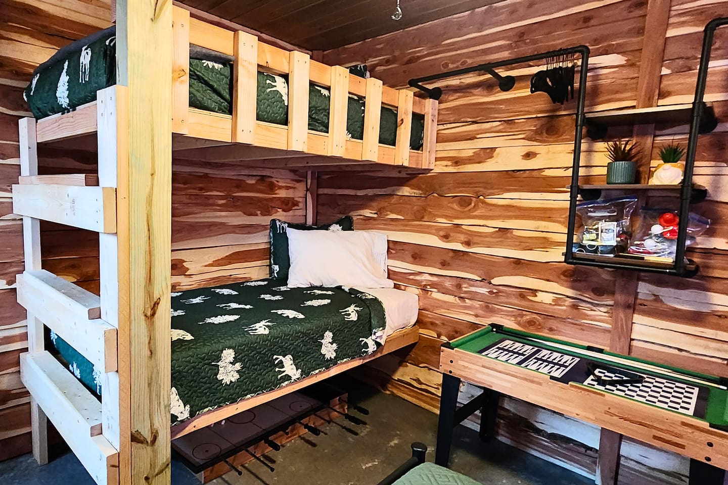This playful bunk room is perfect for kids or friends, featuring twin log-style bunks with woodland bedding, a mini game table, and rustic pine walls. Shelves are stocked with fun activities to keep everyone entertained during their stay.








