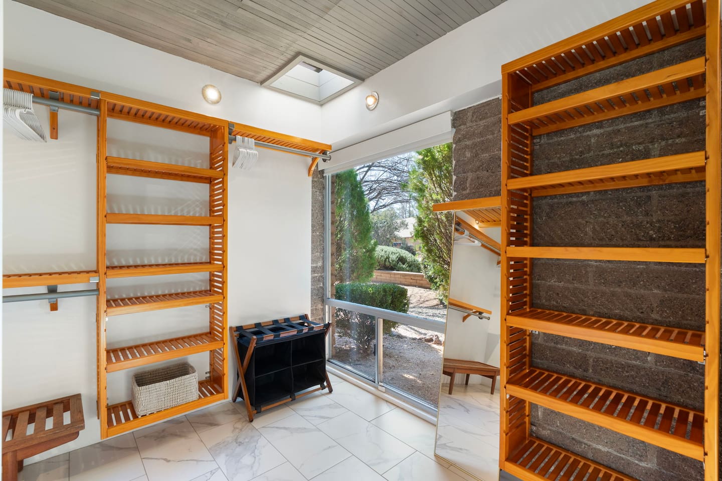 Spacious walk-in closet with custom wood shelving, abundant hanging space, and natural light — thoughtfully designed to keep everything organized and easily accessible.
